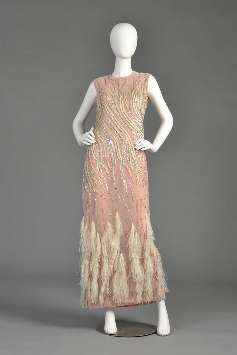 Spectacular 1980s Ruben Panis beaded gown with ostrich feather hem. Pale blush colored chiffon with bright poppy-colored lining. High neck with feather-like design and ostrich feathers around the hem. Known in the 1980s for dressing celebs and
