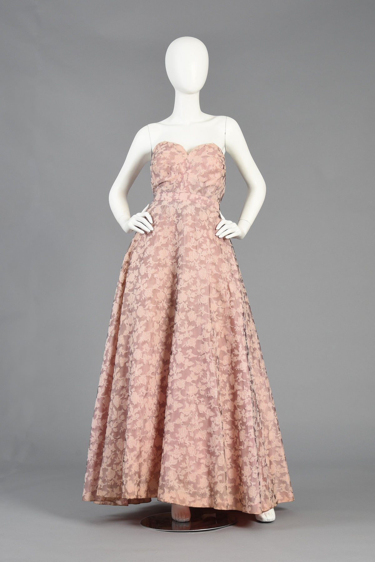 Bustown Modern is so proud to present this stunning 1950's Nettie Rosenstein lace evening gown. A spectacular find in excellent vintage condition. Pale pink silk taffeta body with black and white floral lace overlay. Strapless sweetheart neckline