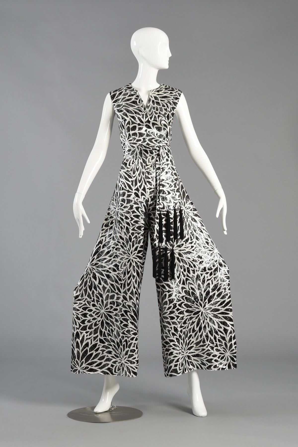 Incredible 1960's brocade jumpsuit. We can't get over the insane metallic black and silver floral pattern! Amazing construction with fitted bodice and super wide legs. Also includes the fringed sash which, of course, is just the icing on the cake.