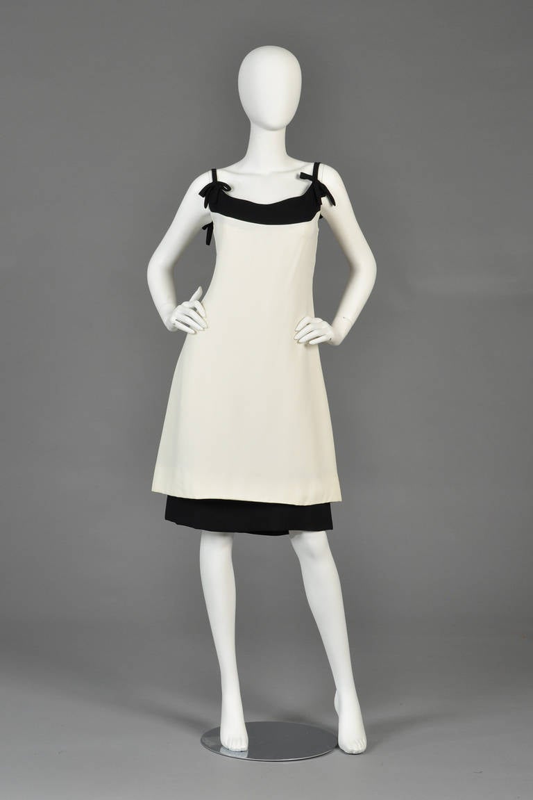 Classic 1960s ivory and black cocktail dress by Harou. Ultra wide bustline with applied bows at each strap + tiered skirt. Mid to heavy weight crepe with rear zipper. Best fits modern size large. Excellent vintage condition - freshly cleaned and