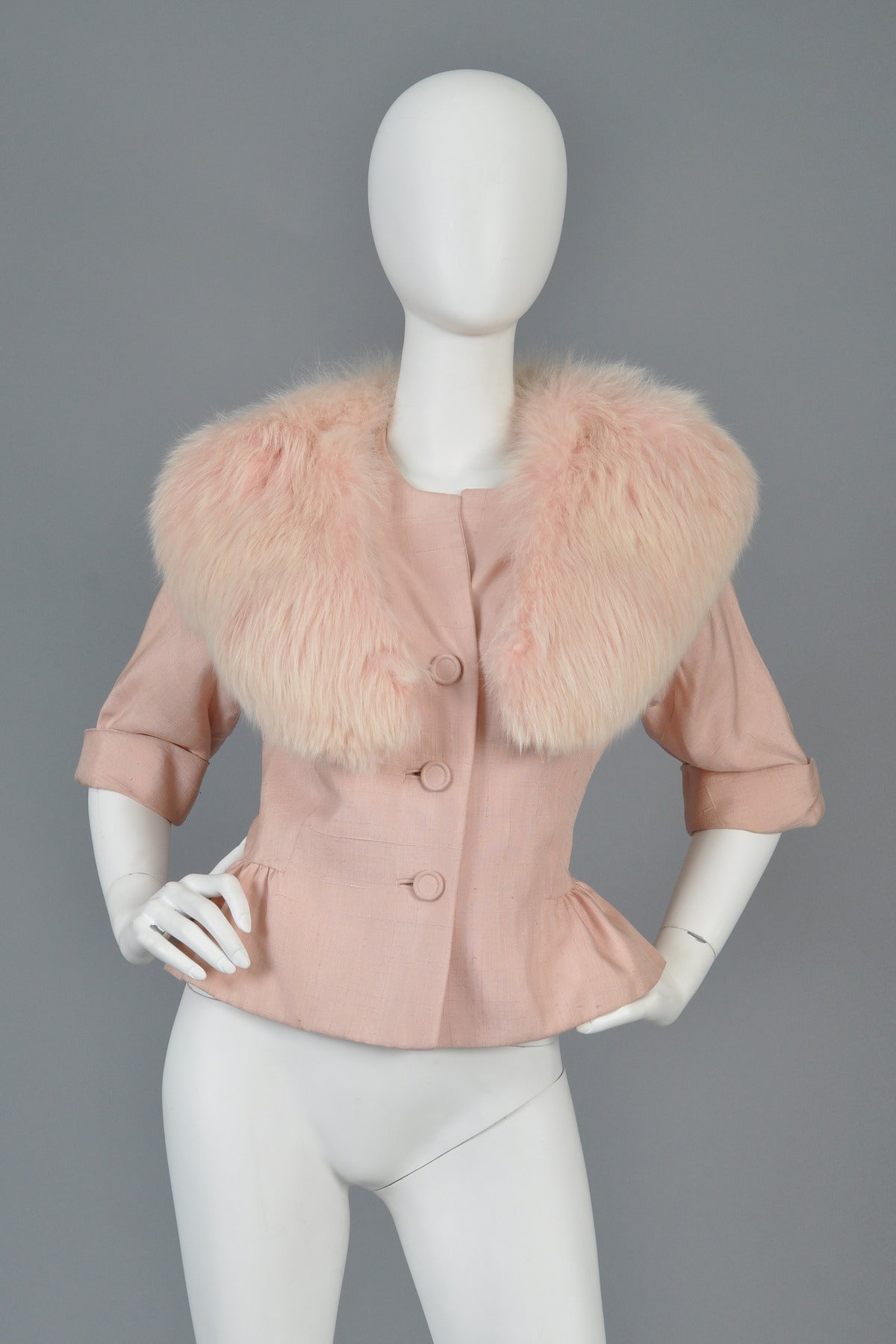 Lovely 1950s pink slubbed silk suit jacket. Absolutely stunning pale pink color with button front, nipped waist, gathered + ruched hips, 3/4 length sleeves and MASSIVE genuine pink fox fur collar. Best fits sizes small-medium. Excellent vintage