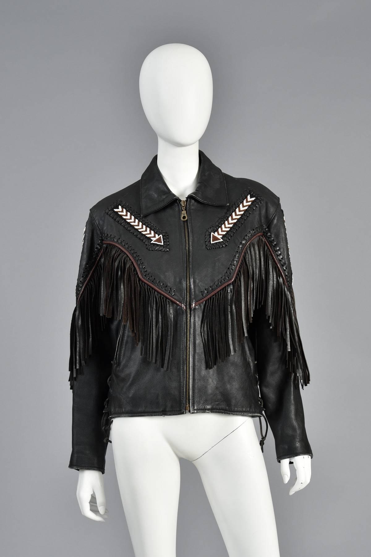 Super awesome southwest inspired  black leather vintage biker jacket. Such a killer piece! This piece features a super skinny fit with zip front, corseted sides, beaded native-inspired details and fringe galore. We especially love the contrasting