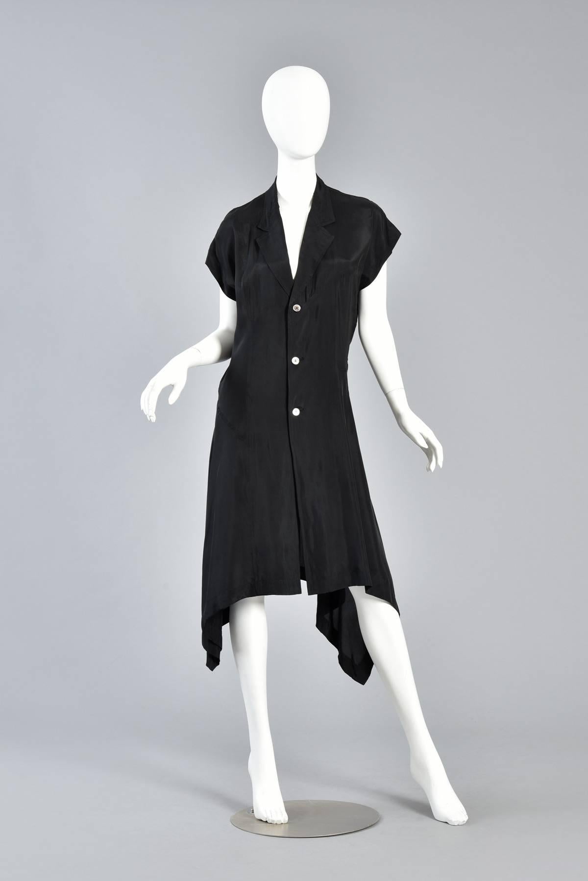 Classic (as far as Comme des Garcons is concerned anyway) asymmetrical black dress. Simple button front with slouchy shoulders, deep-cut collar and asymmetric draped hem. We love the gathering at the waist on the wearer's left side! Flattering on a