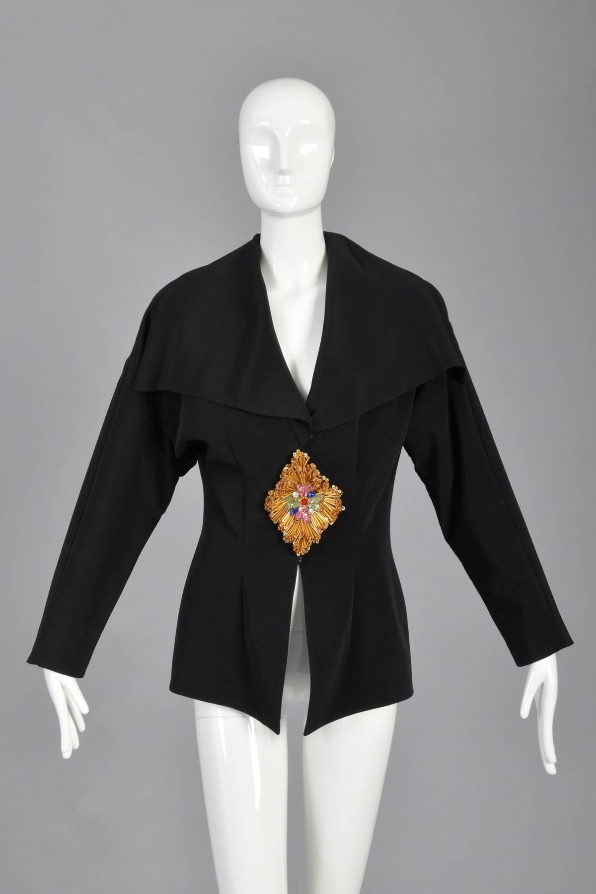 Fantastic vintage late 80s/early 90s Naeem Khan jacket for Lillie Rubin. Draped blazer with cape top. Huge Schiaparelli-inspired gold sequined + beaded diamond at waist. Hidden snap + hook & eye closures.

MEASUREMENTS
Bust: 38