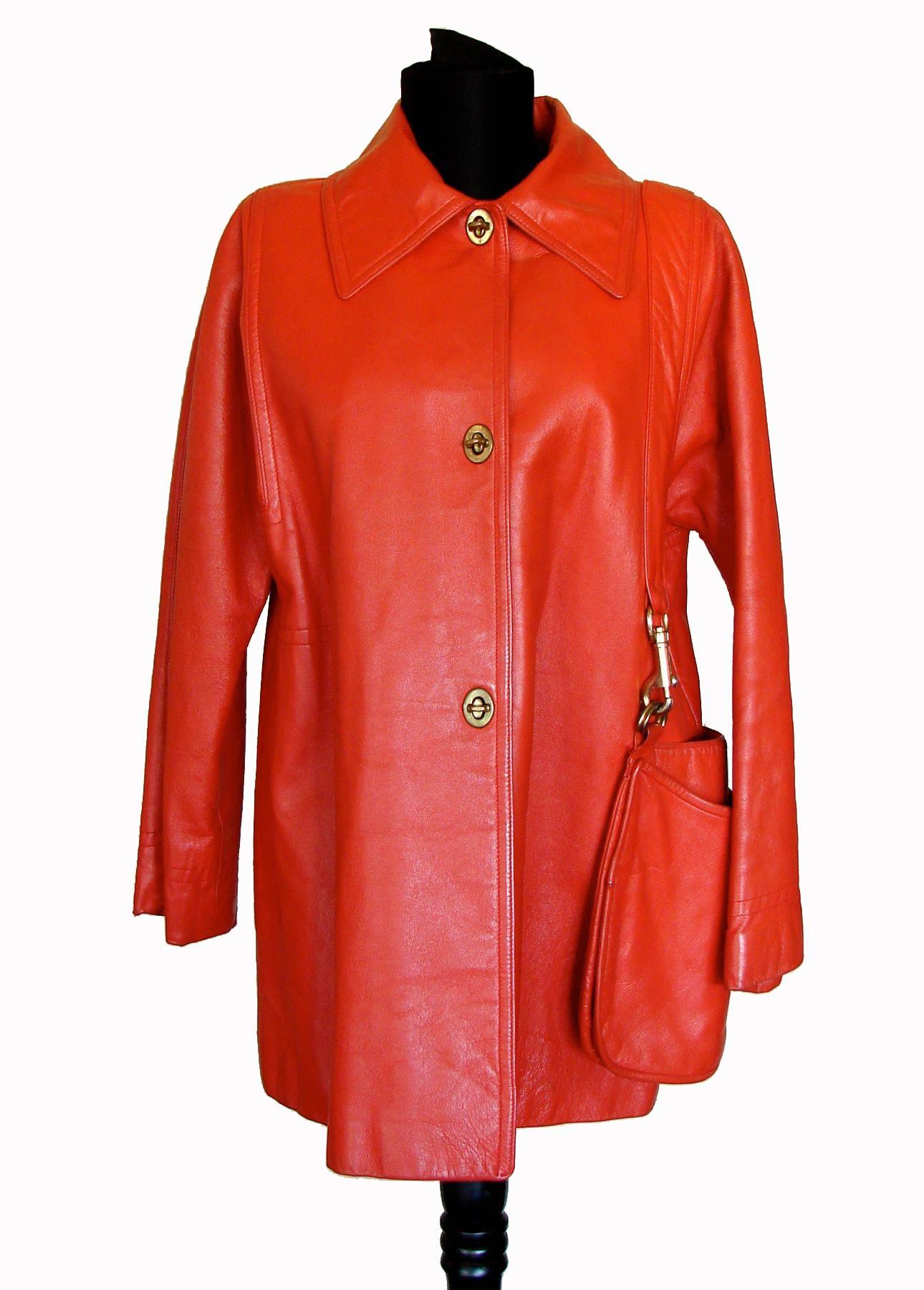 This incredibly chic and practical jacket was designed by Bonnie Cashin during her time at Sills in the 1960s.  Made from a tomato red or dark orange leather, it features brass turnlock fasteners down the front, and an attached matching hobo bag,