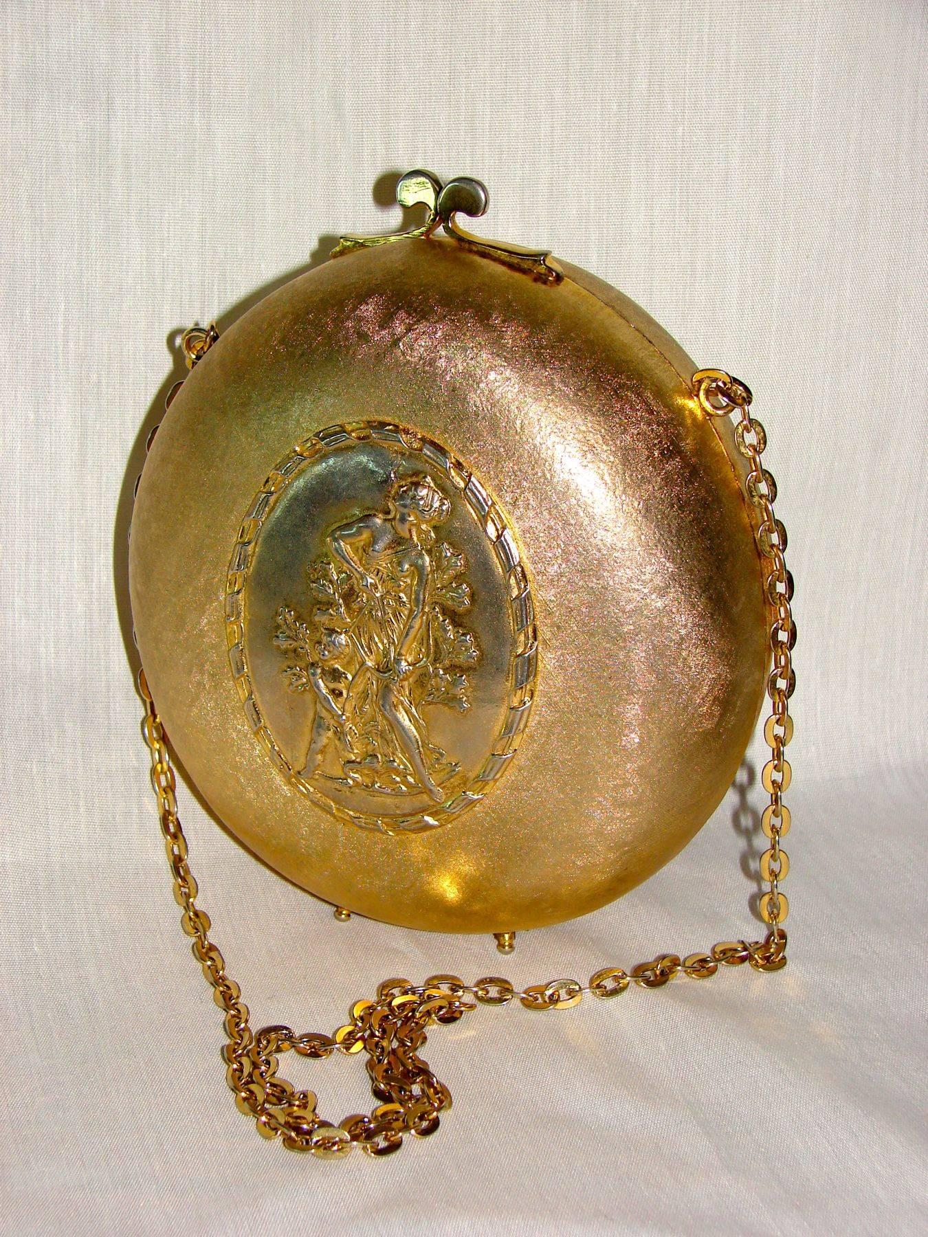 A gilt metal evening bag attributed to Rosenfeld circa 1965.  Made from a gilt exterior, it features a center plate in silver with neoclassical style figures.  Inside is lined in gold velvet and still retains its 'Made in Italy' tag.

In very good