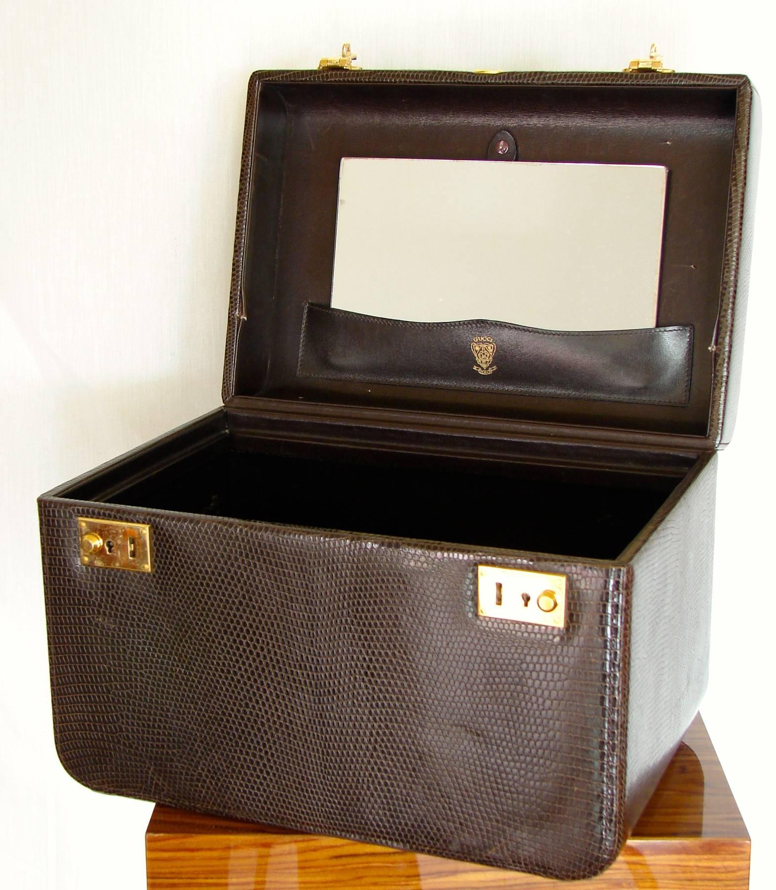 Travel in style with this gorgeous vintage train case from Gucci.  Made from a lizard-embossed leather in a rich chocolate brown, it features gold hardware and is lined in black leather.  Inside you'll find a removable mirror, leather straps that