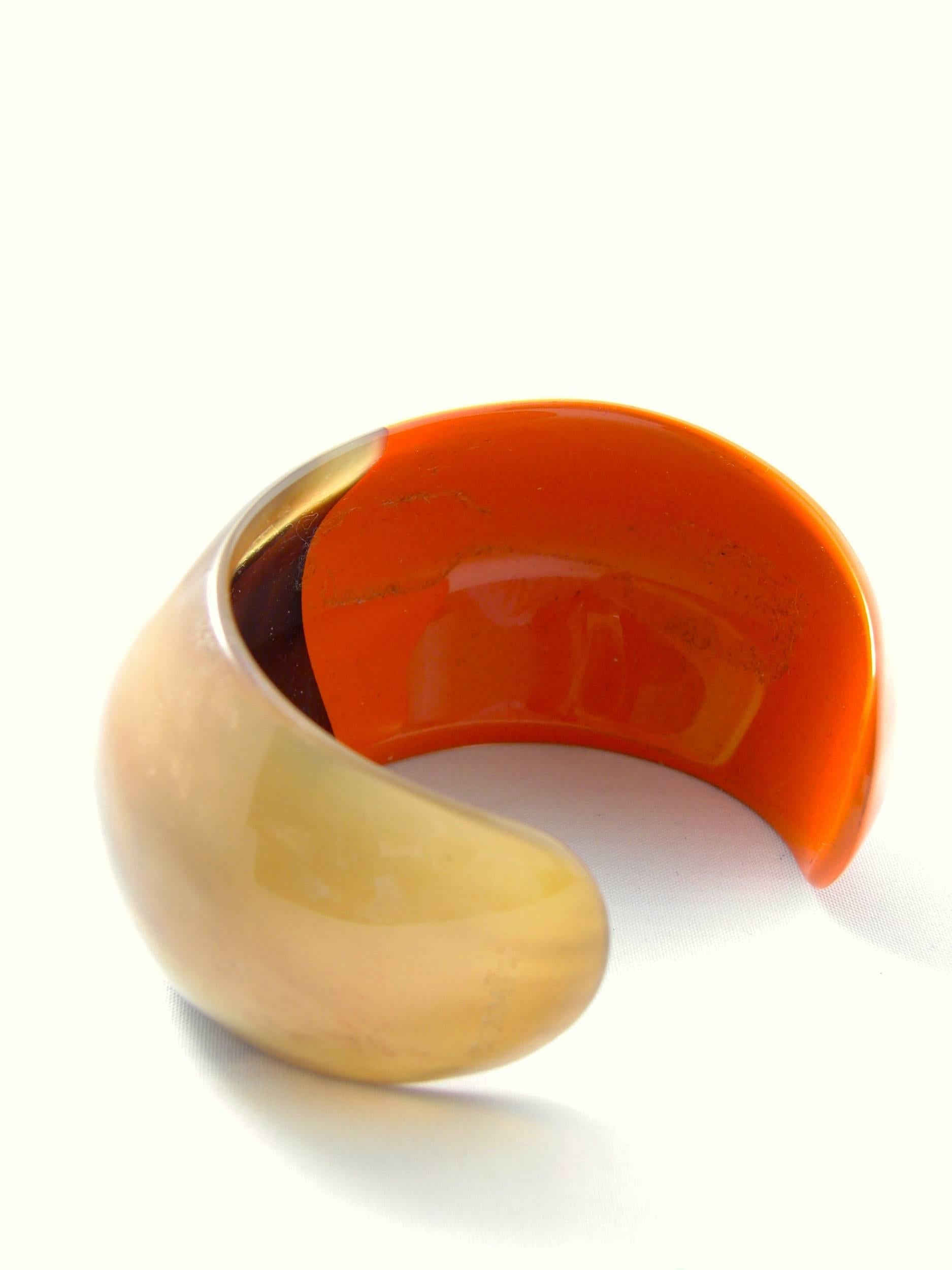 This cuff bracelet is from Hermes and is made from natural horn and resin in shades of reddish orange and natural tan and brown.  Hard to find and no longer manufactured by Hermes, this piece is in excellent pre-owned condition with only minor