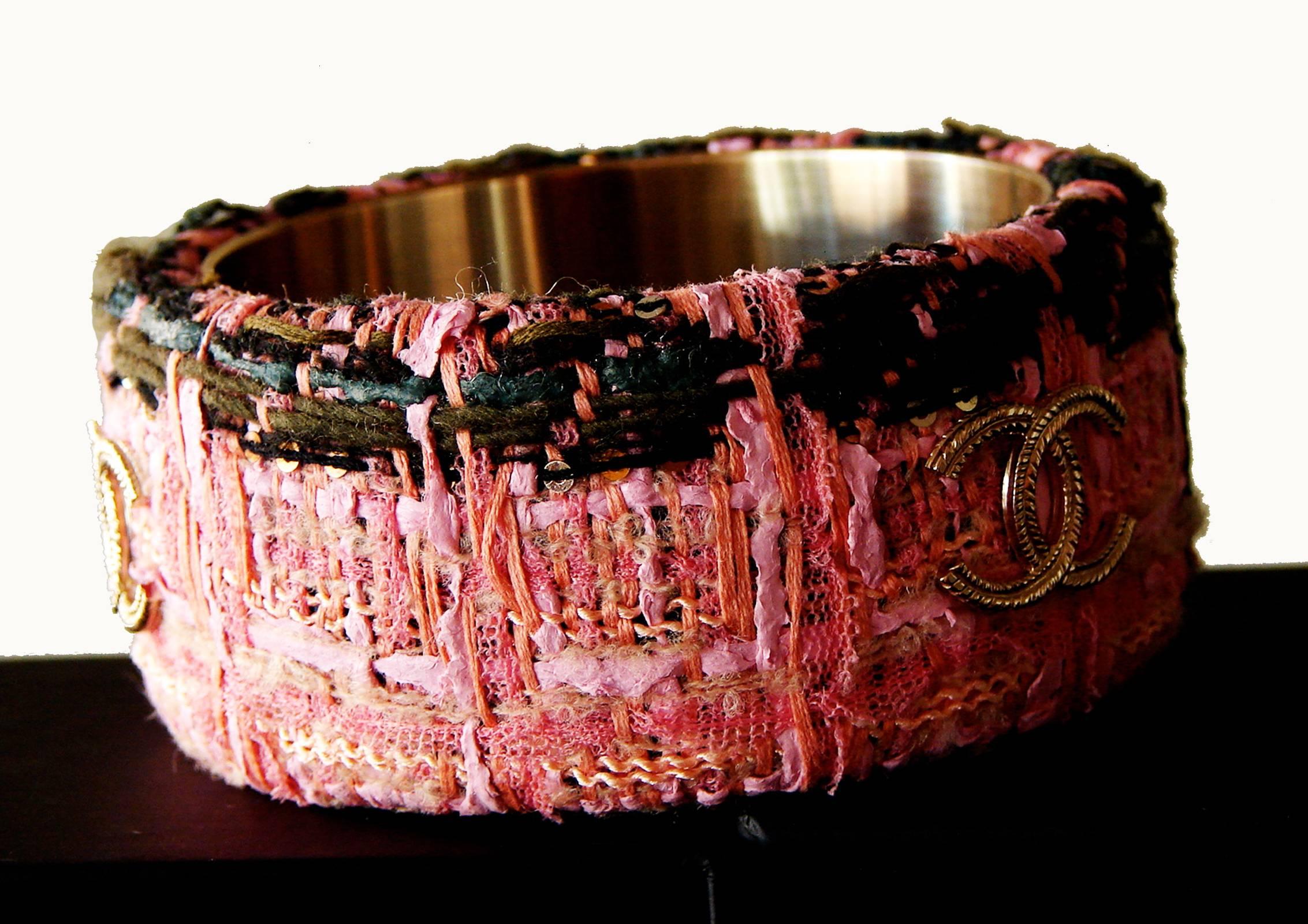 From the Chanel 2013 collection, a chunky Lesage tweed bangle bracelet in shades of pink and black with gold hardware.  This piece measures 1.5in H and approximately 2.75in in diameter.  In excellent condition, there are very minor surface scratches