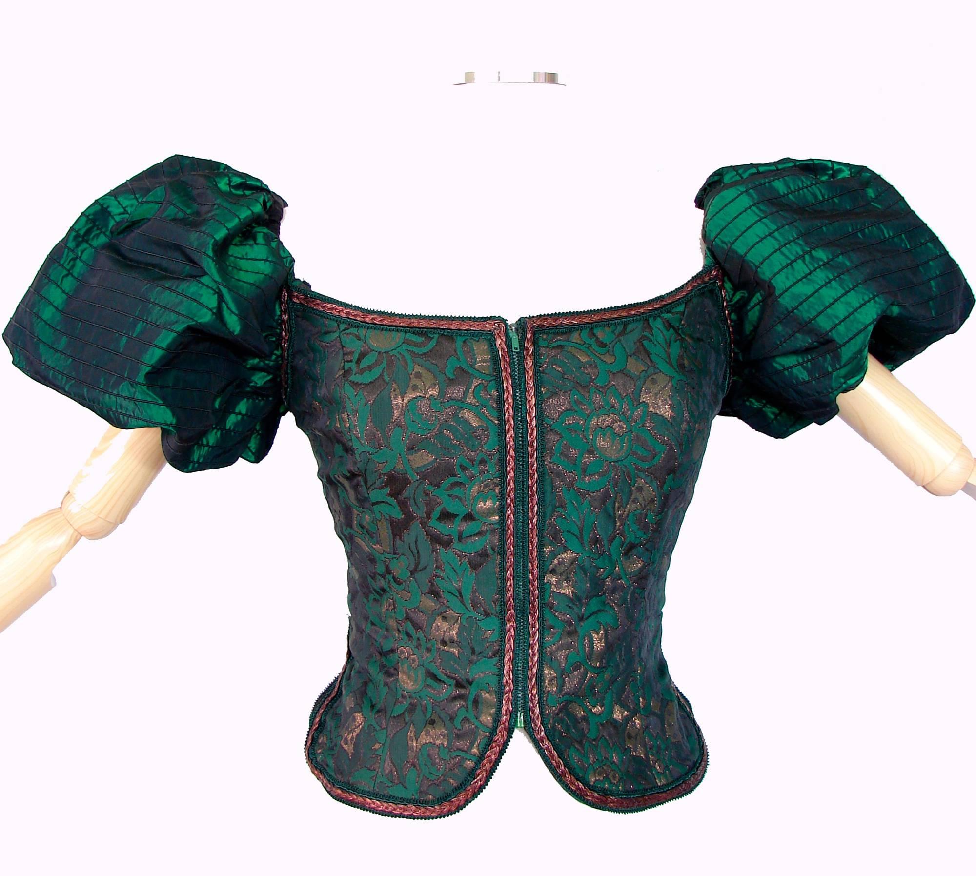 We love this corset top from VICTOR COSTA!  Made from a metallic green satin, it features slim black embroidered stripes on the puffed sleeves, with metallic gold braid trim.  The bodice features an abstract leaf pattern and fastens in front with a