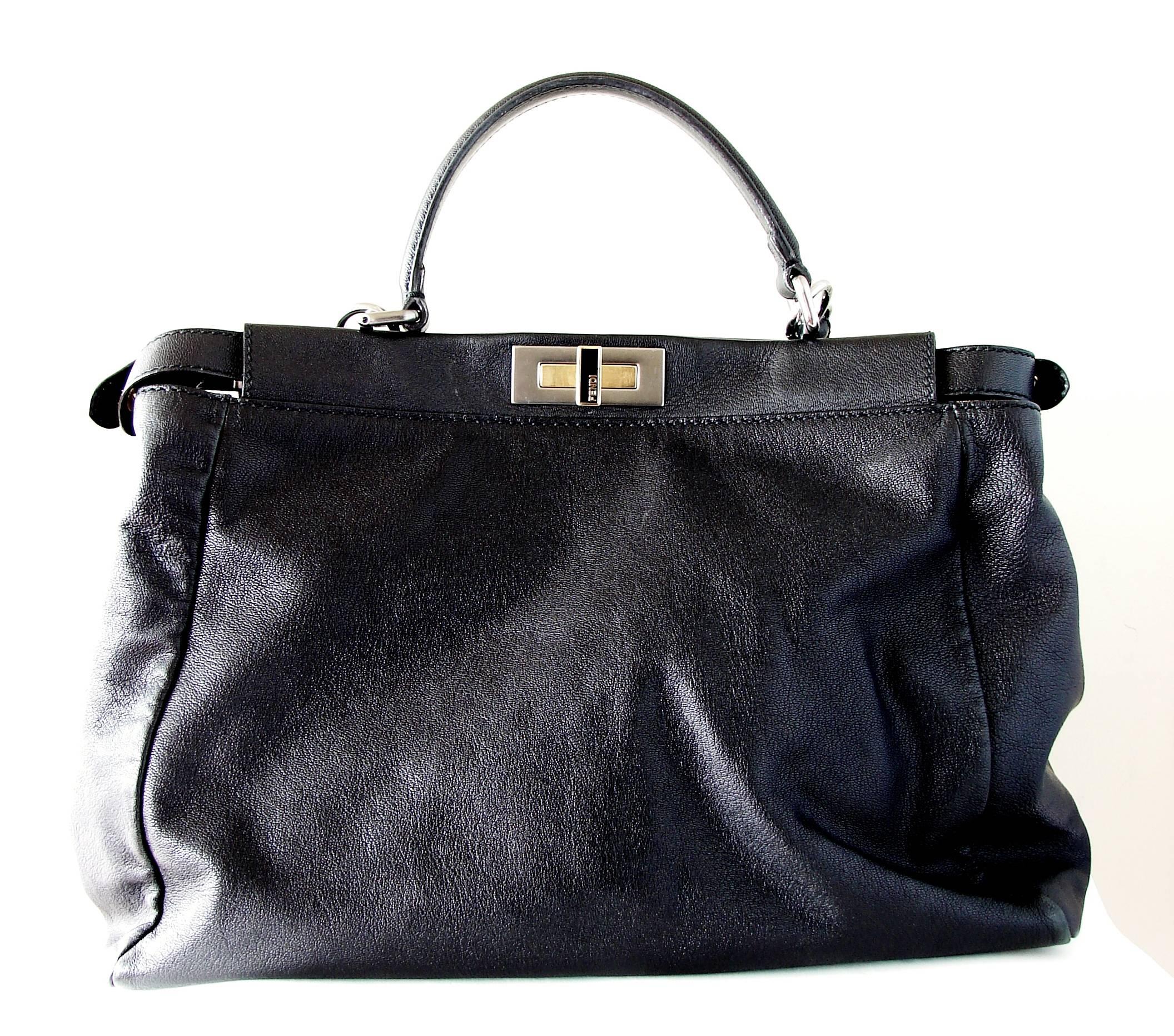 This incredible black leather handbag is from Fendi and features their stylish peekaboo design.  This substantial bag features two large sections, both lined in Fendi Zucca fabric, and features both gold and silver hardware throughout. It comes with