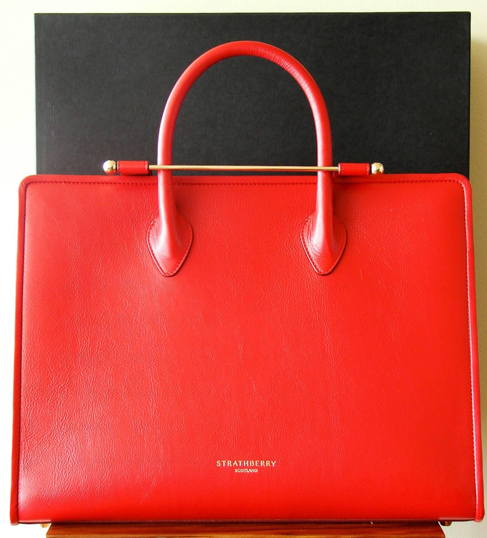 Incredibly chic bag from Strathberry Scotland! Made from luxe ruby red calfskin, it comes with a removable shoulder strap for hands-free carry. Brand new and never carried condition, it comes with its dust cover & box.  Measures 15.75in H x
