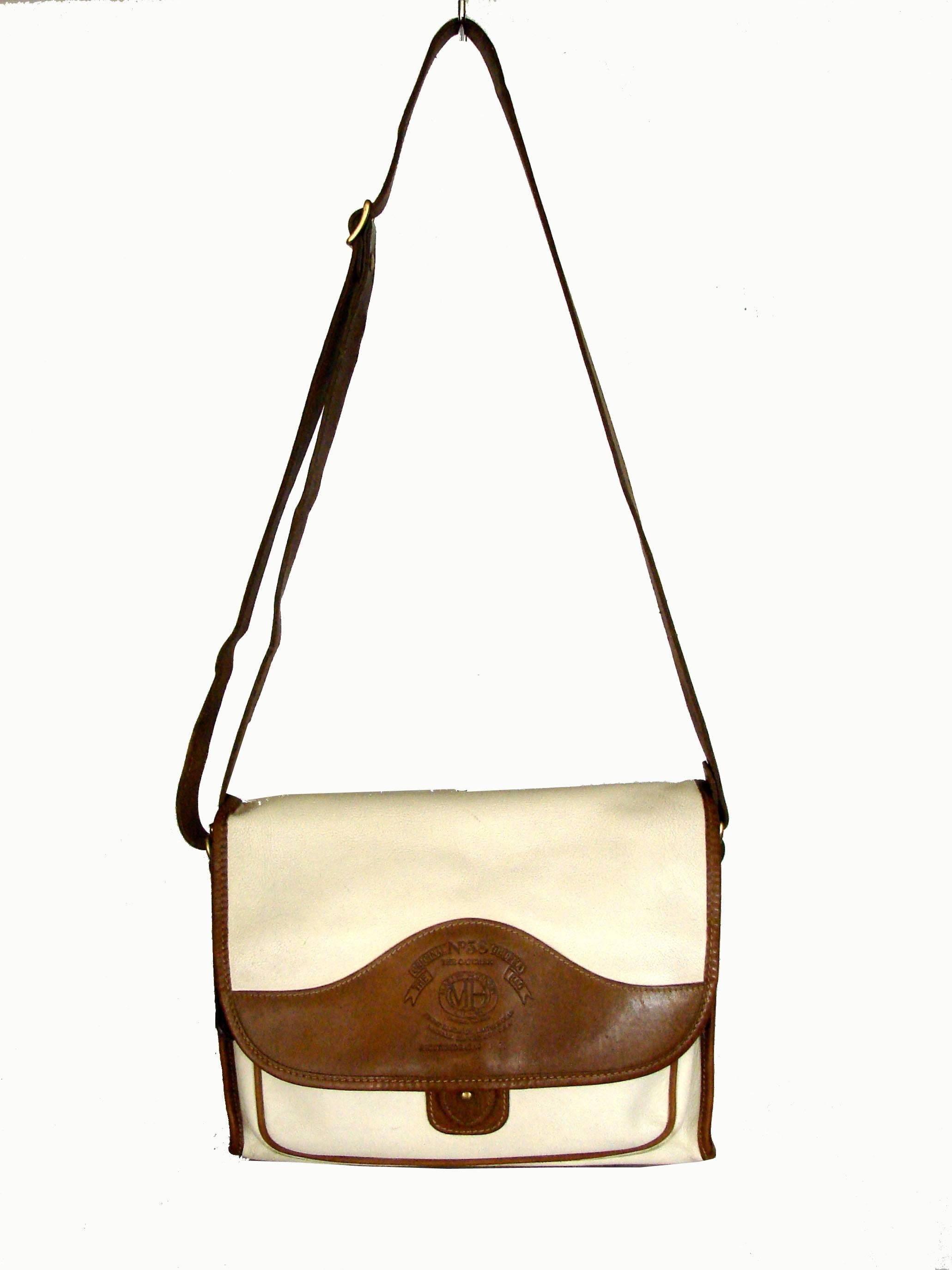 Hard to find handbag from Ghurka, from the 1980s is made from ivory Khyber Calf and trimmed in saddle leather.  Adjustable shoulder strap allows for cross body carry.  Measurements: 8.5