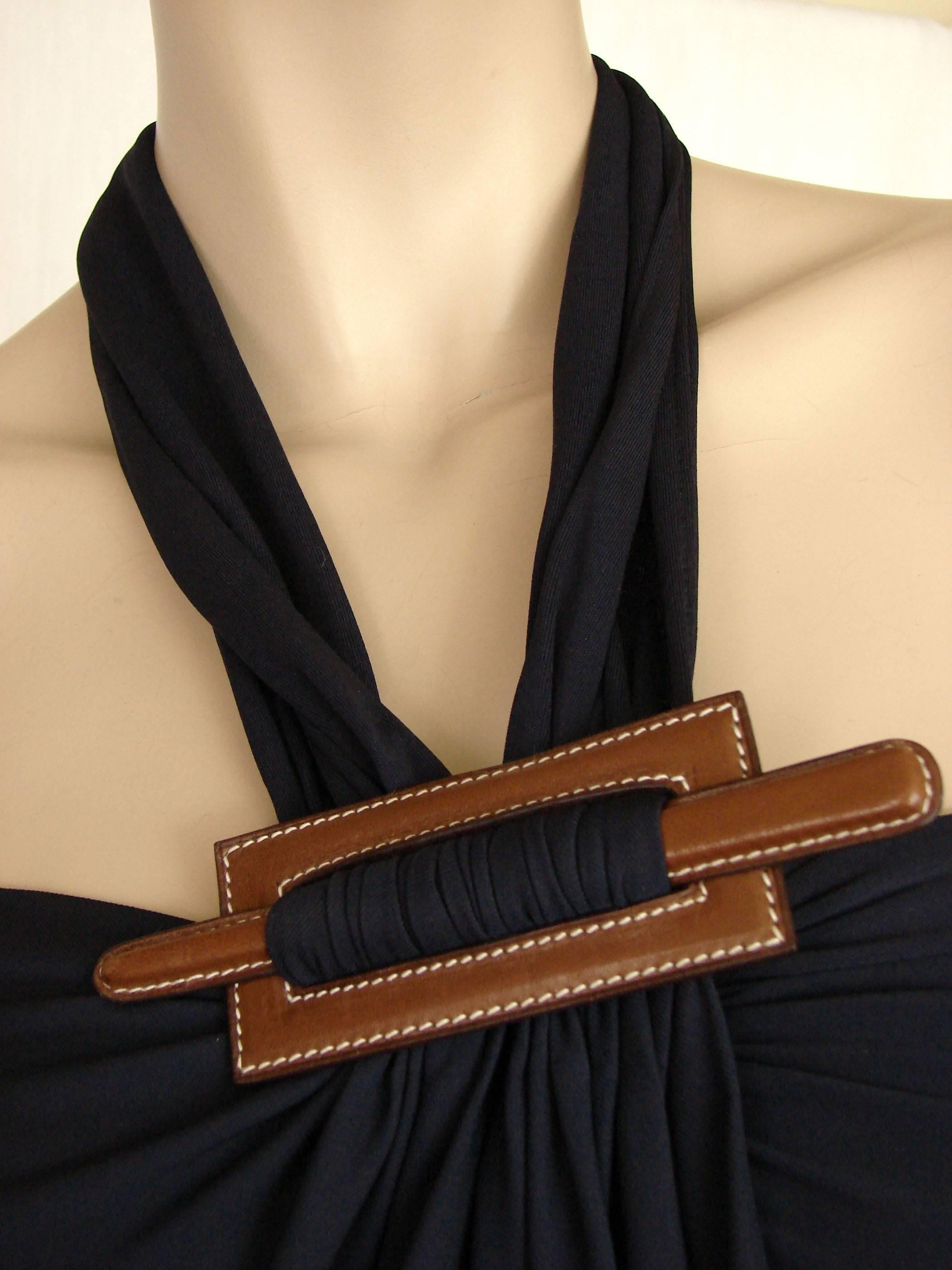 This incredibly chic long dress or gown is from Hermes and was designed by Jean Paul Gaultier in 2007.  Made from a navy viscose jersey fabric, it features a Barenia leather focal point at the chest.  This piece fastens wrap style with simple