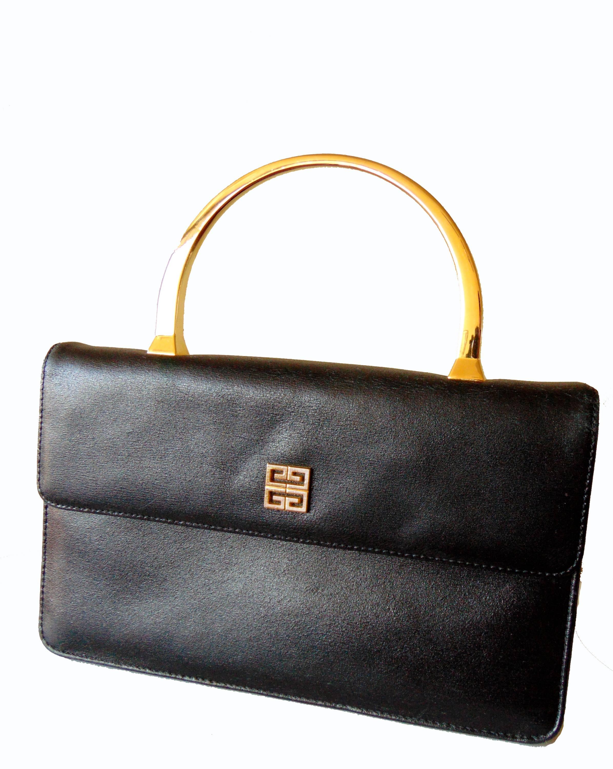 This little black bag is so chic! Made by Givenchy in the late 1980s, it features a black leather exterior with gold logo on the flap, and a shiny gold metal top handle.  The interior is lined in black calfskin and it features one small flat zip
