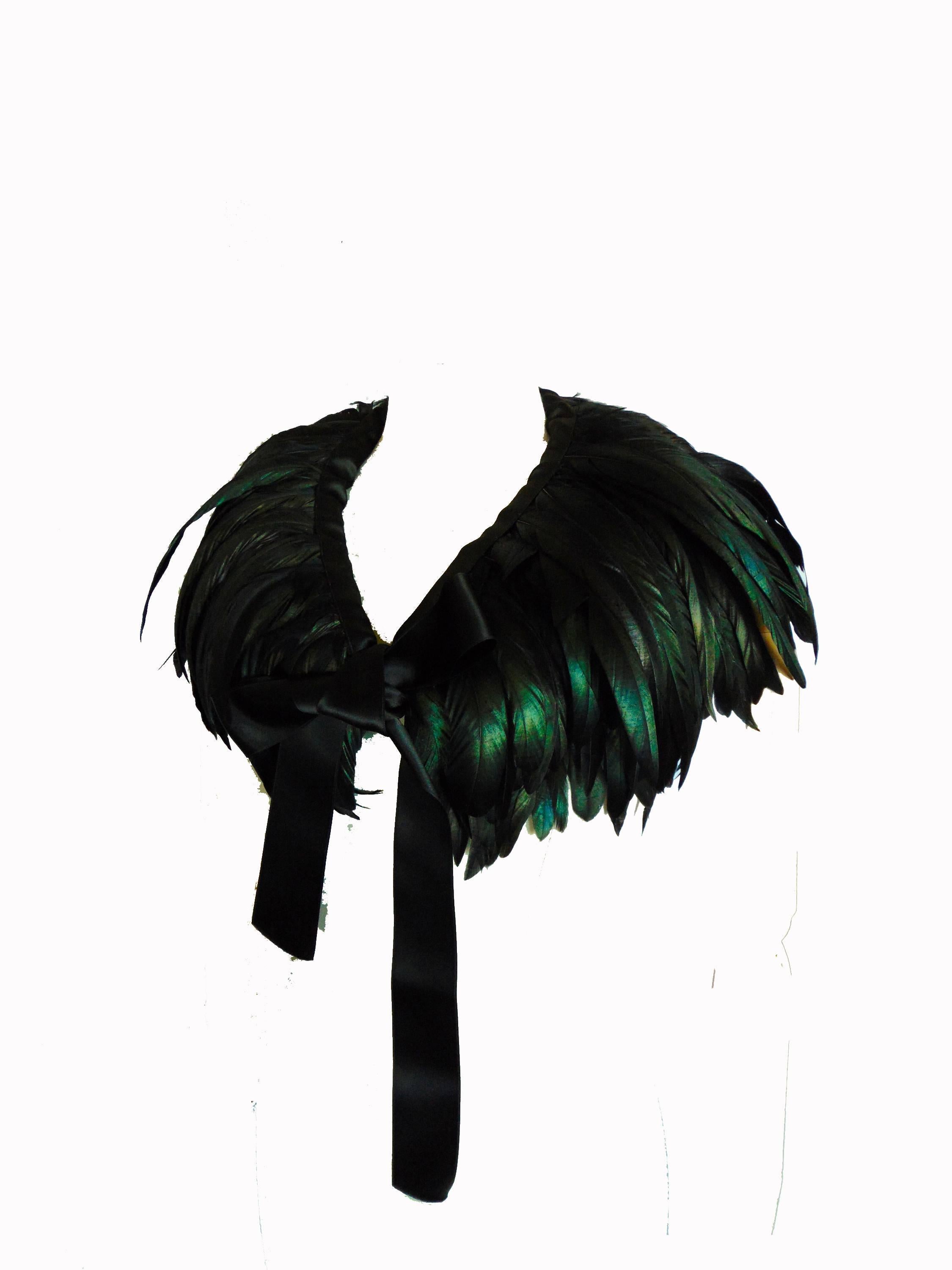 This incredible feathered cape or oversized collar was made by Yves Saint Laurent in the late 1970s.  Constructed with iridescent emerald and black feathers, this piece fastens with long black silk ties.  Fully-lined in black silk. In excellent