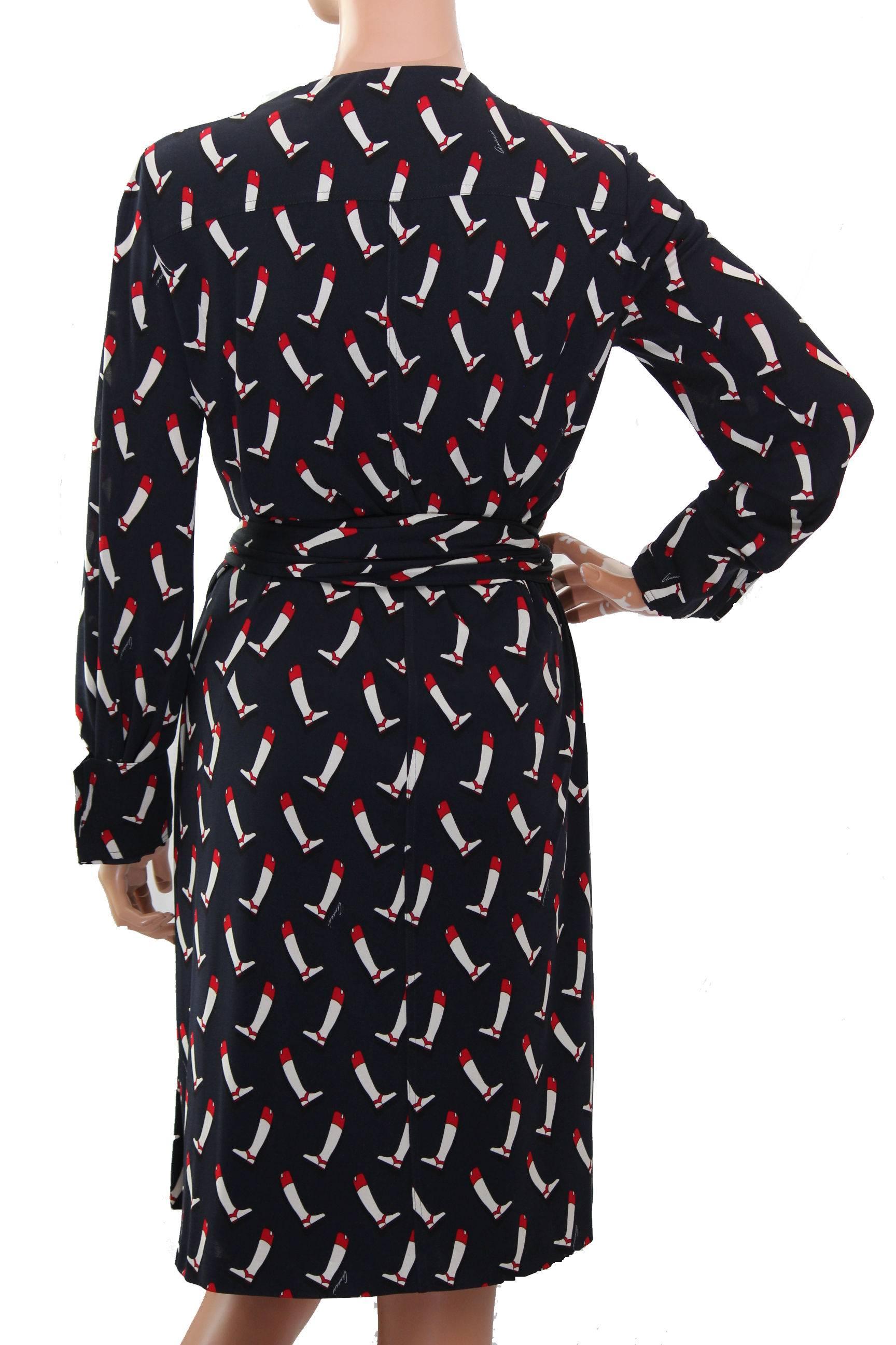 This vintage silk dress was made by Gucci and features a charming equestrian boot print on a navy background! Wrap style, it fastens with buttons and cinches with an attached silk belt and gold-tone metal horse bit closure. 
Lined in lightweight