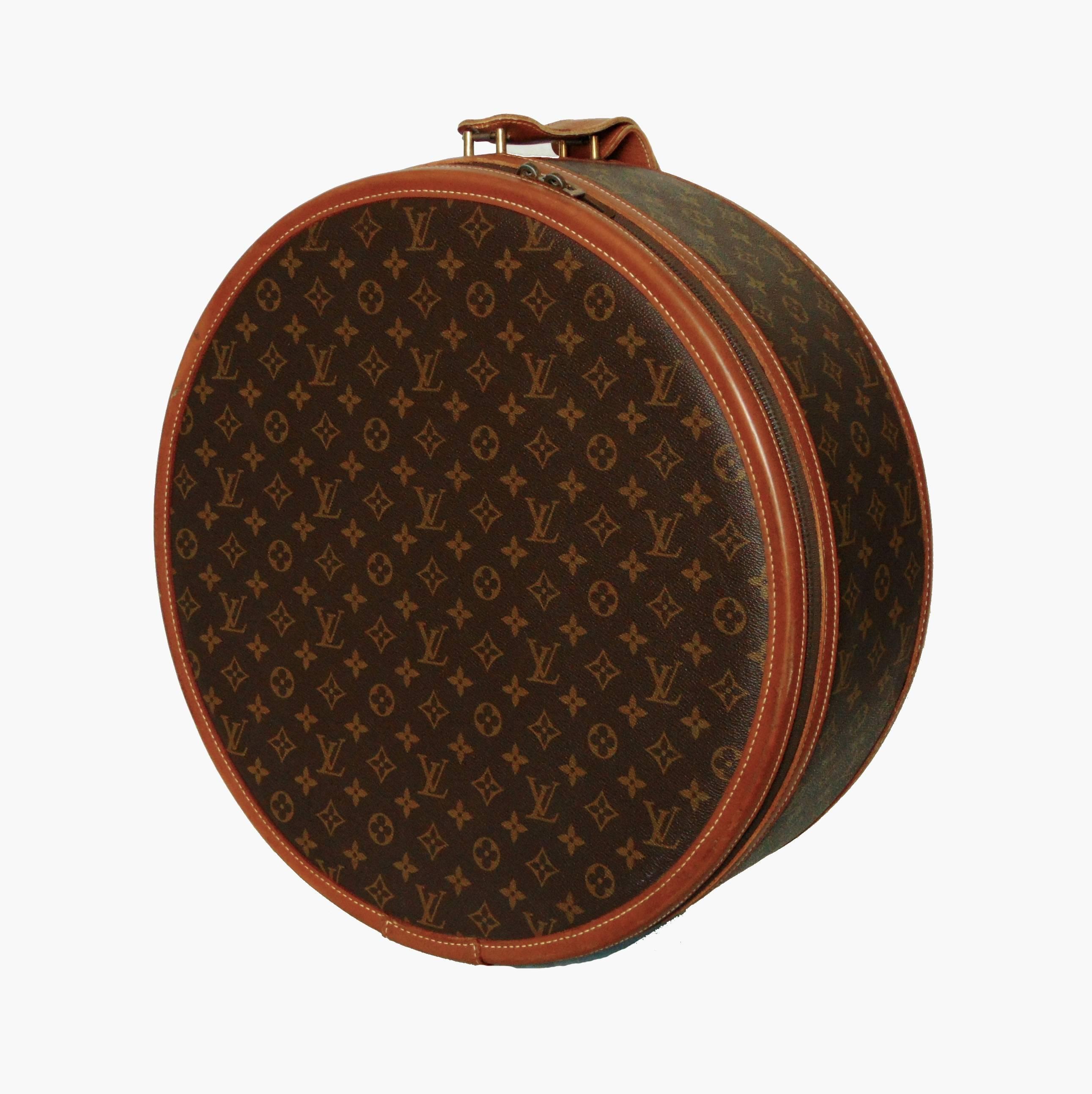 This rare hat box or travel case was made in the 1970s by The French Company, under special license by Louis Vuitton.  Made from their signature monogram canvas, this piece is trimmed in tan saddle leather and fastens with a chunky brass zipper. 