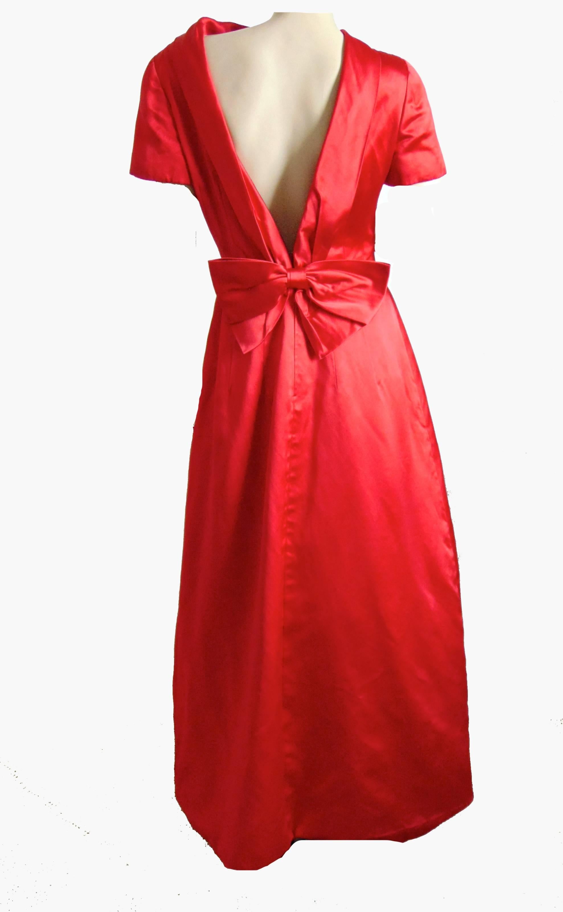 This brilliant gown was designed by Valentino in the 1990s.  Made from a vibrant red silk satin fabric, it features a collared neckline and low cut back with bow detail.  Fully-lined and in excellent condition, we note some small thin pulls to the