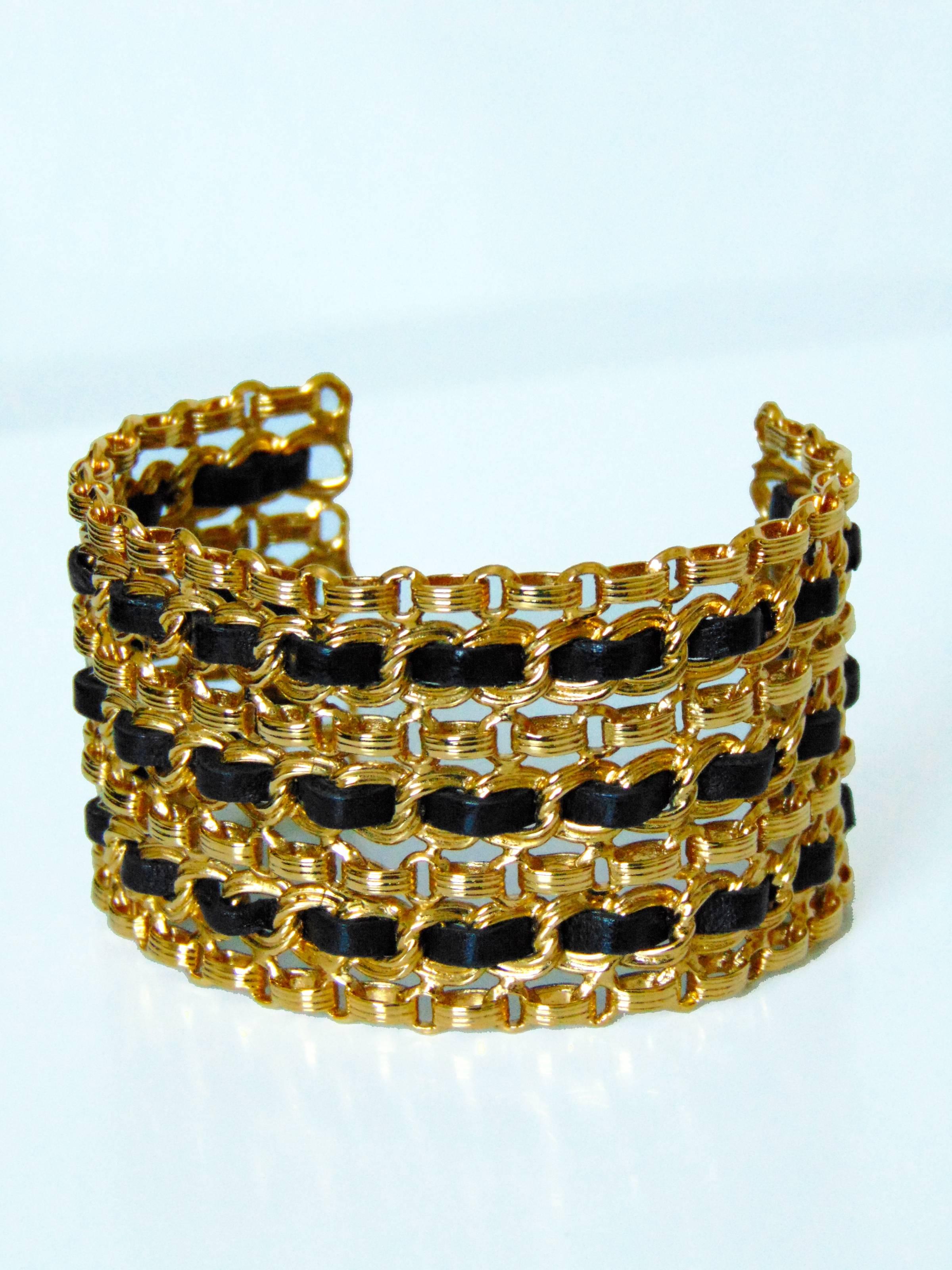 This fabulous wide cuff bracelet was made by Chanel, likely in the early 1980s, Made from gold metal chains, it features black leather strips interwoven throughout.  In excellent condition.  It measures appx 2.75in diameter x 2in H.  Stamped CHANEL.