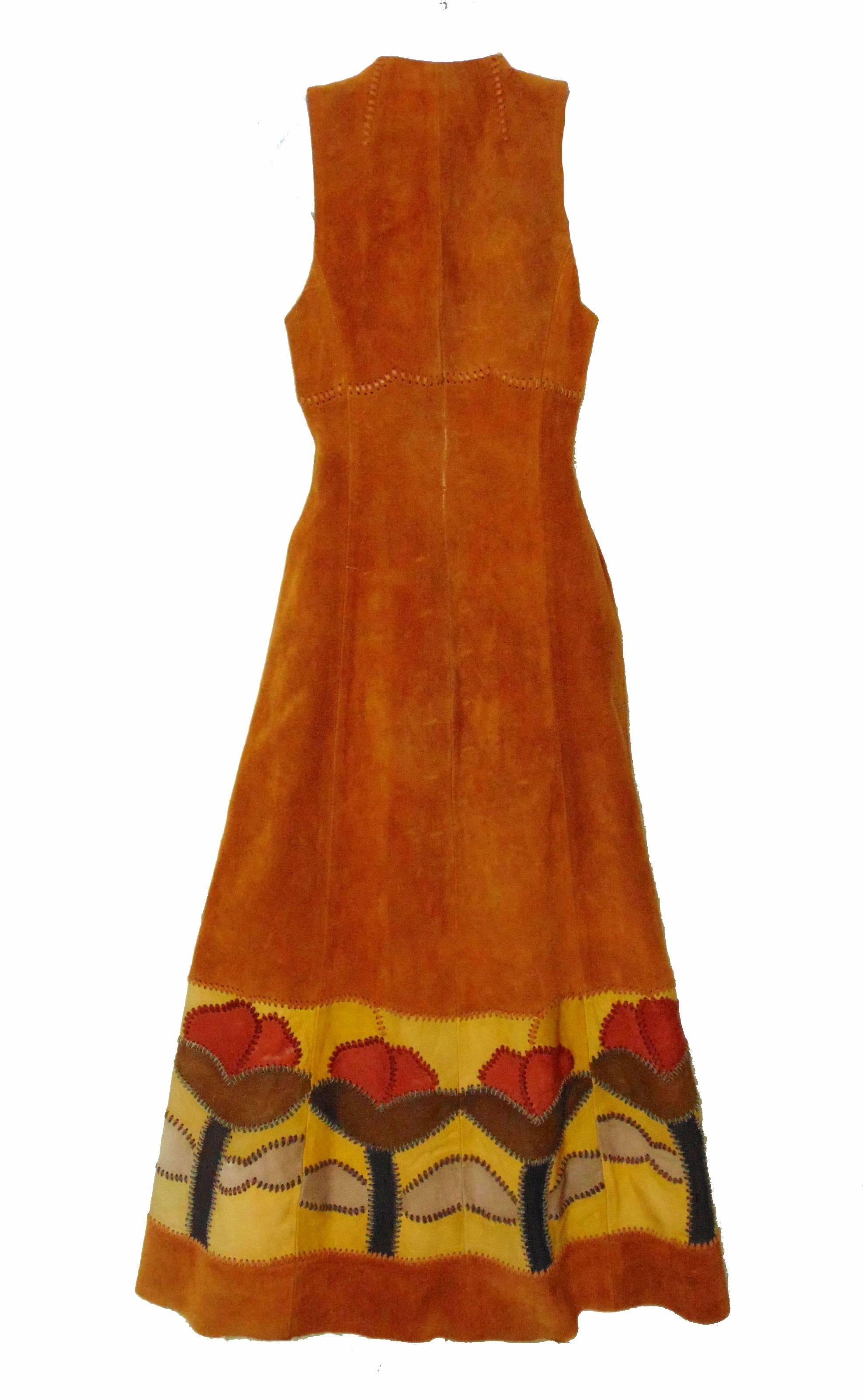 This unusual long festival dress or vest was designed by Char, Charlotte Blankenship de Vasquez, in the early 1970s.  Made from tan suede leather, it features whip stitching and leather floral inserts at the bottom hem and waist ties. So chic - it