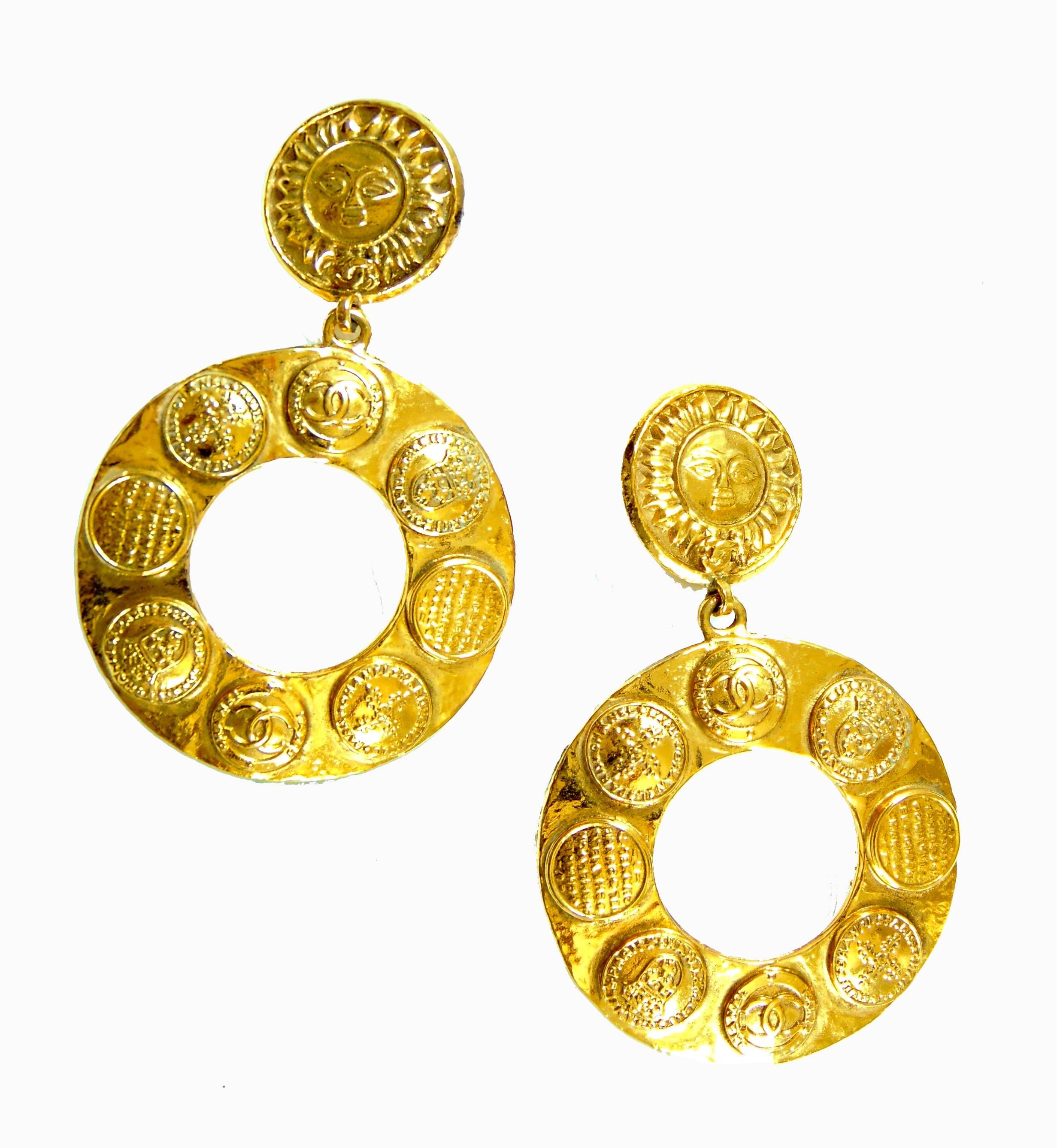 Here's a fabulous pair of MASSIVE hoop earrings from CHANEL! Made from gold metal, these babies measure appx 3.5in long x 2in wide. The clip portion has a sun motif and the hoops feature the CC logo and various medallions throughout. In excellent
