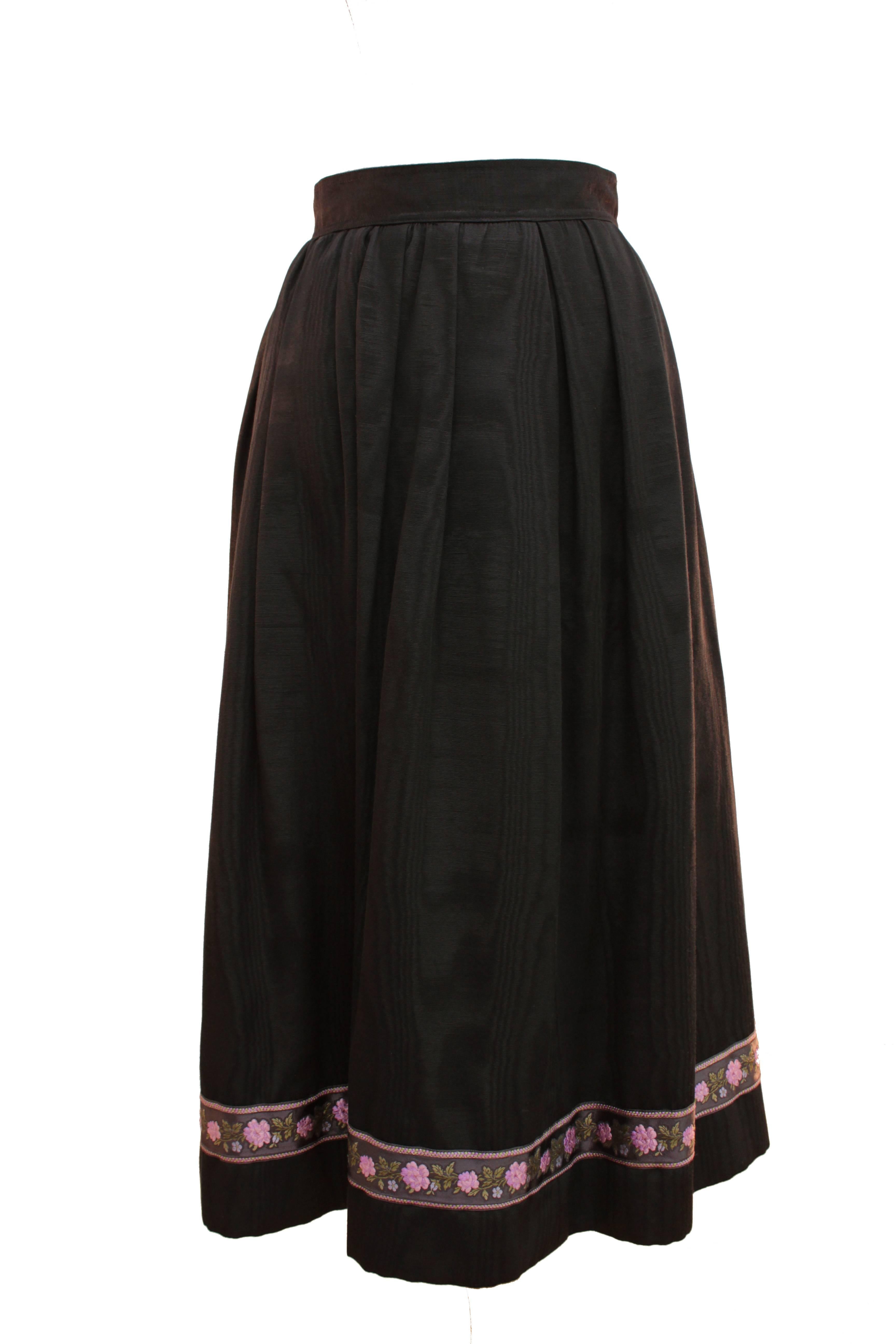 This incredible black moire silk skirt was designed by Yves Saint Laurent circa 1976. It's constructed with a high waistband and full skirt, and features an embroidered floral motif at the hem and hidden side pockets.  In excellent condition for its