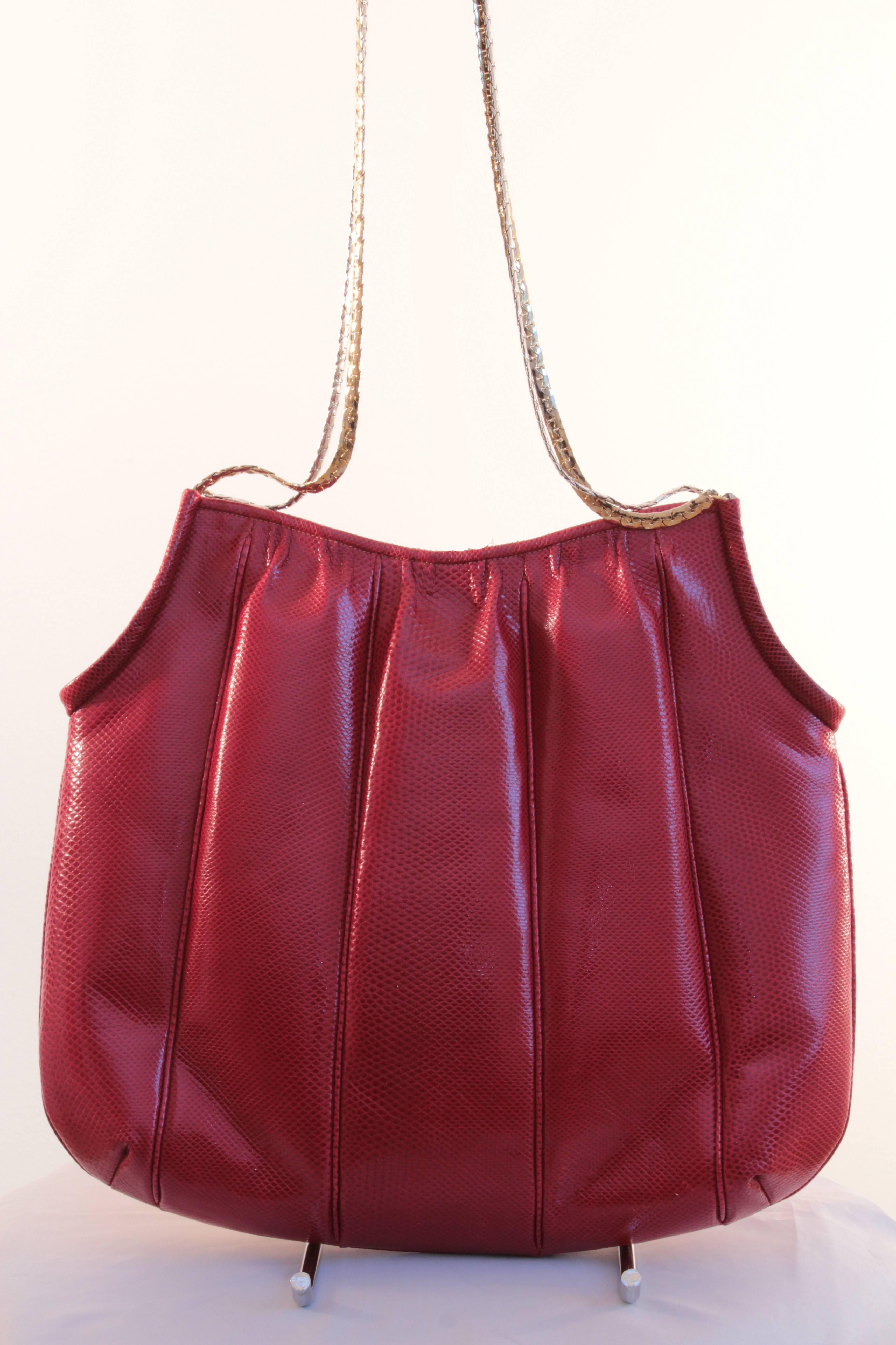 This fabulous red Karung or water snake bag was made by Finesse La Model, likely in the 1980s. It features hidden magnetic closures and two tone chain shoulder straps, gold and silver.  Comes with a silver make up mirror, which fits nicely in the