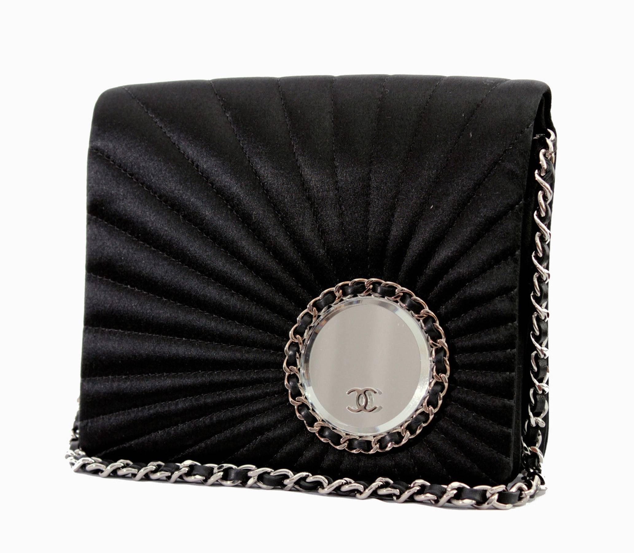 This silk satin evening bag is from Chanel, from their 2002 collection. Made from black silk satin, it features sun ray stitching on its front with a leather and silver chain round mirror attached with CC logo. Accordion-style, this bag is
