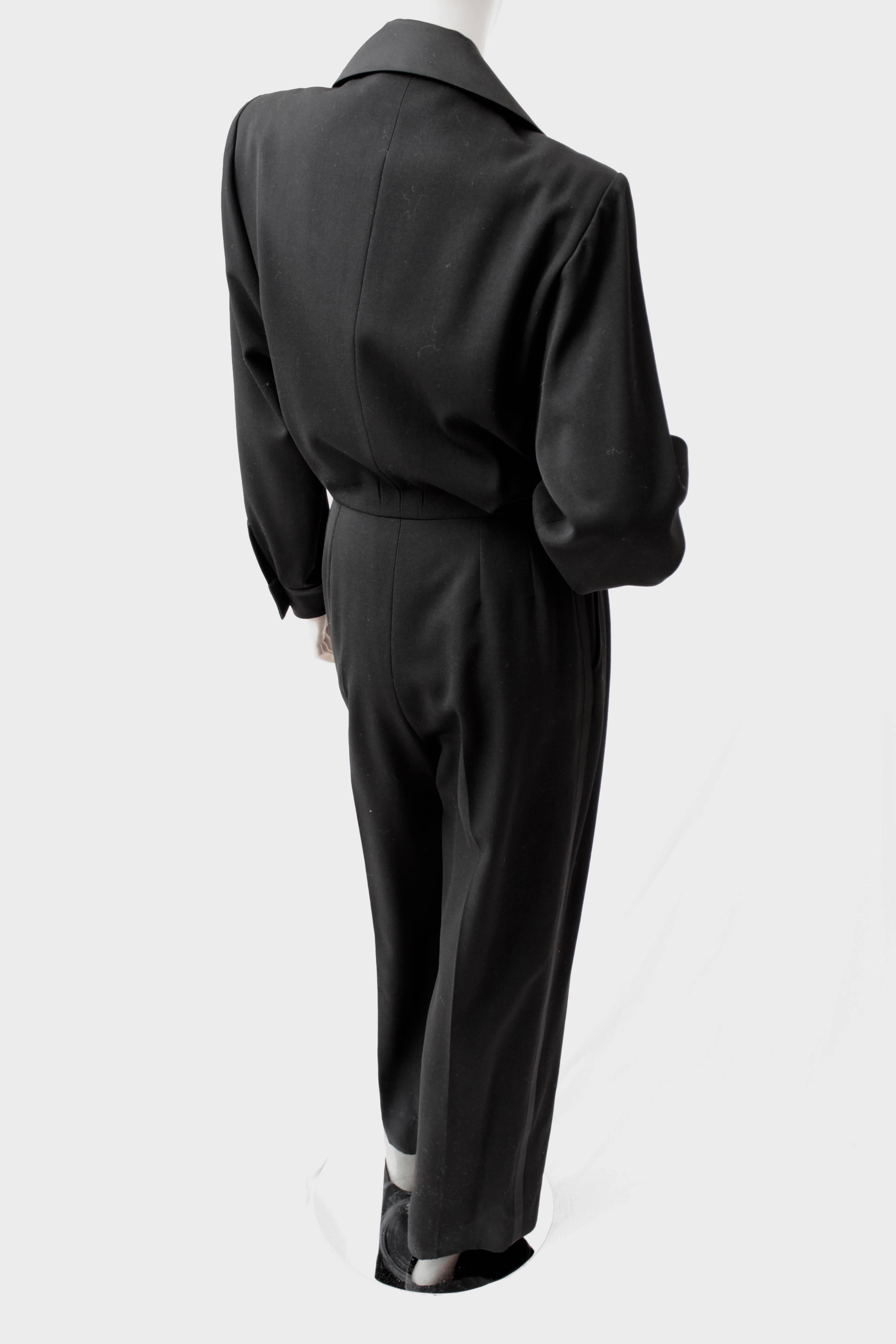 This incredibly chic black jumpsuit was made by Yves Saint Laurent Rive Gauche, most likely in the early 1990s.  Made from wool with silk satin trim, it features YSL's iconic Le Smoking theme in a very sleek jumpsuit with low cut neckline. 