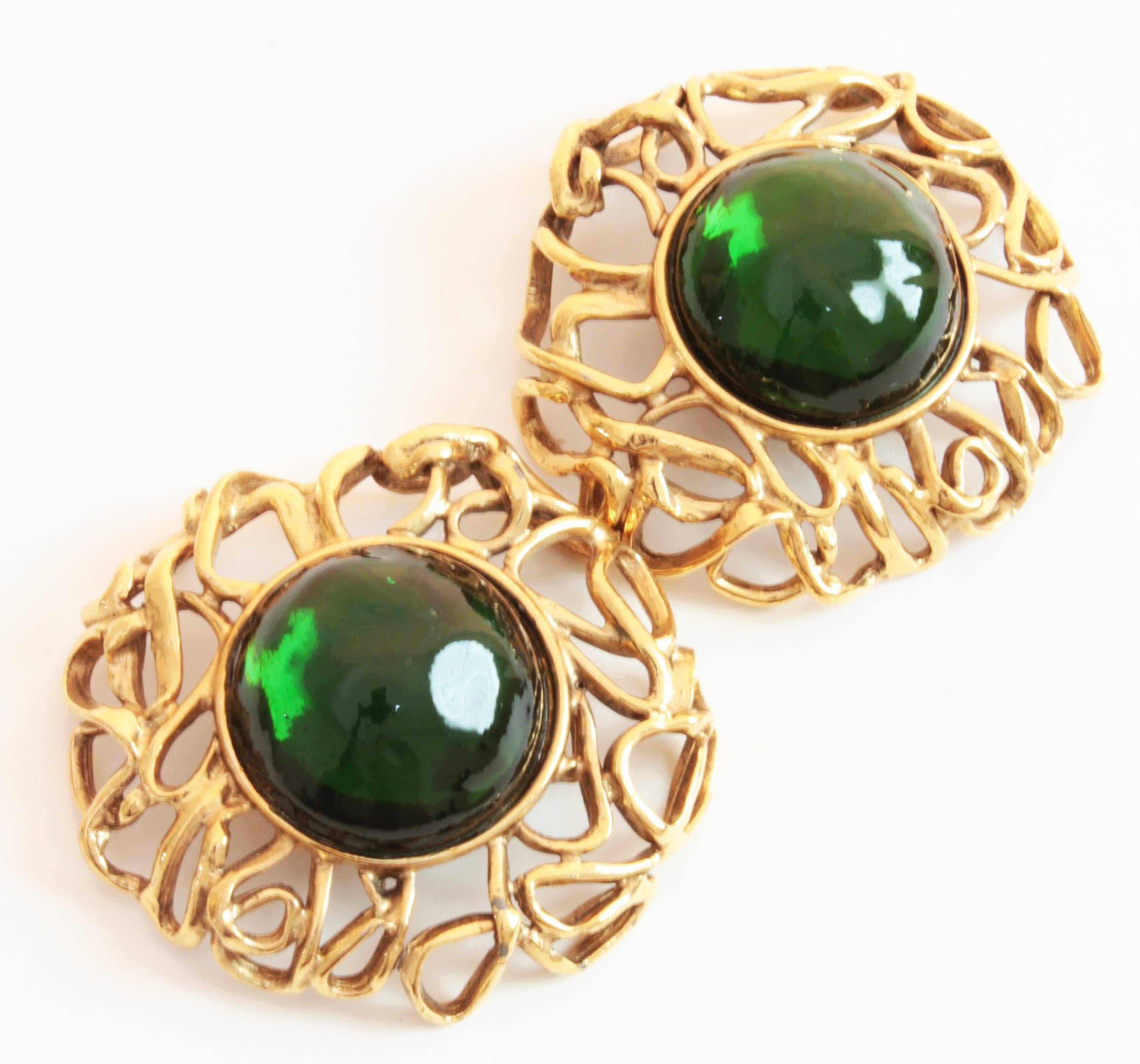 These incredible earrings were designed by Robert Goossens for Yves Saint Laurent in the mid-1970s and feature large emerald green glass cabs set in a swirling gold metal setting. Measuring appx 2.25in in diameter, these earrings are substantial and