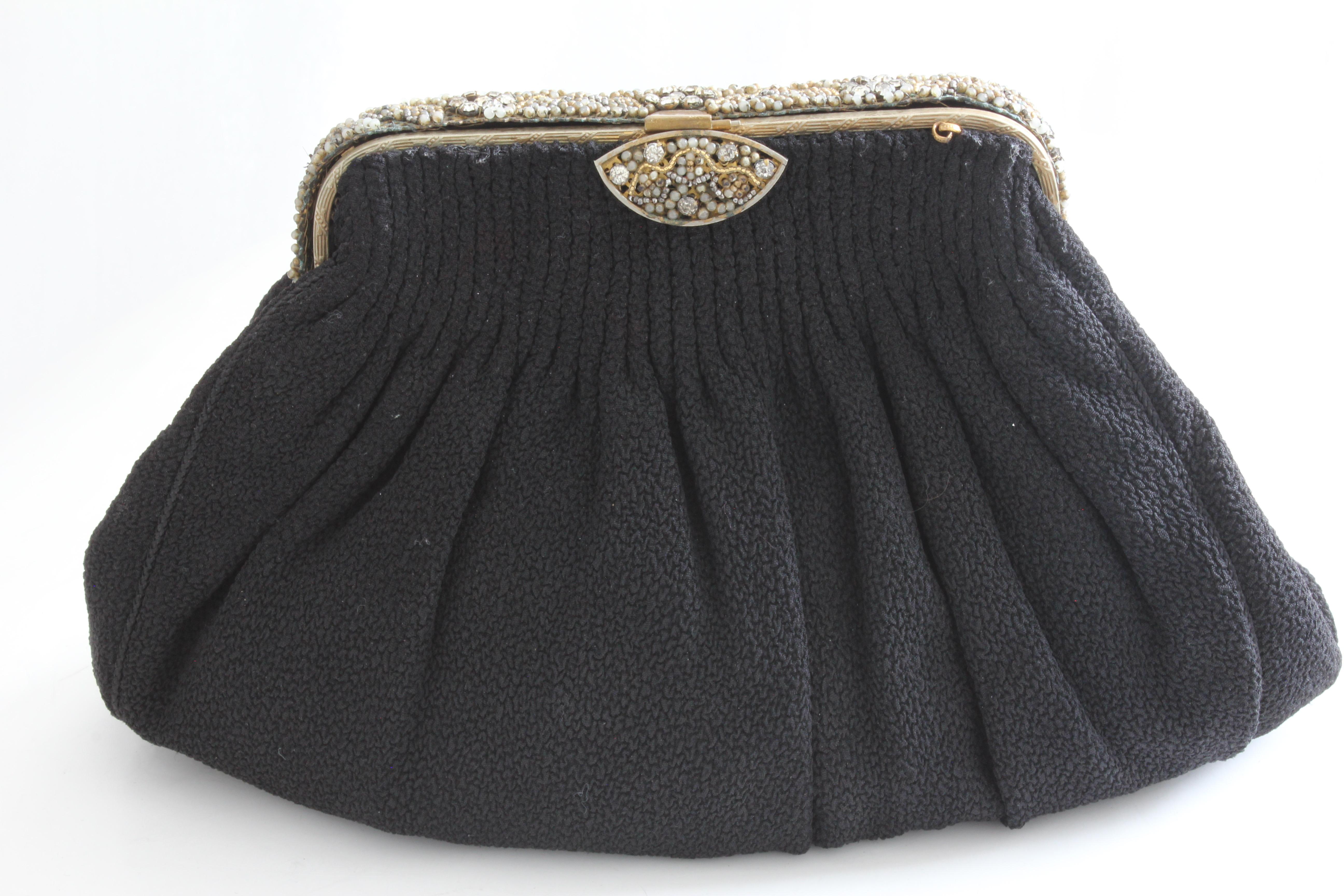 This lovely little bag was made by Custom Bags by Christine, Detroit, most likely in the 1940s.  Made from a nubby black fabric, it features corded seams, a pleated top and a decorative, hinged metal frame with closure clasp.  The interior is lined