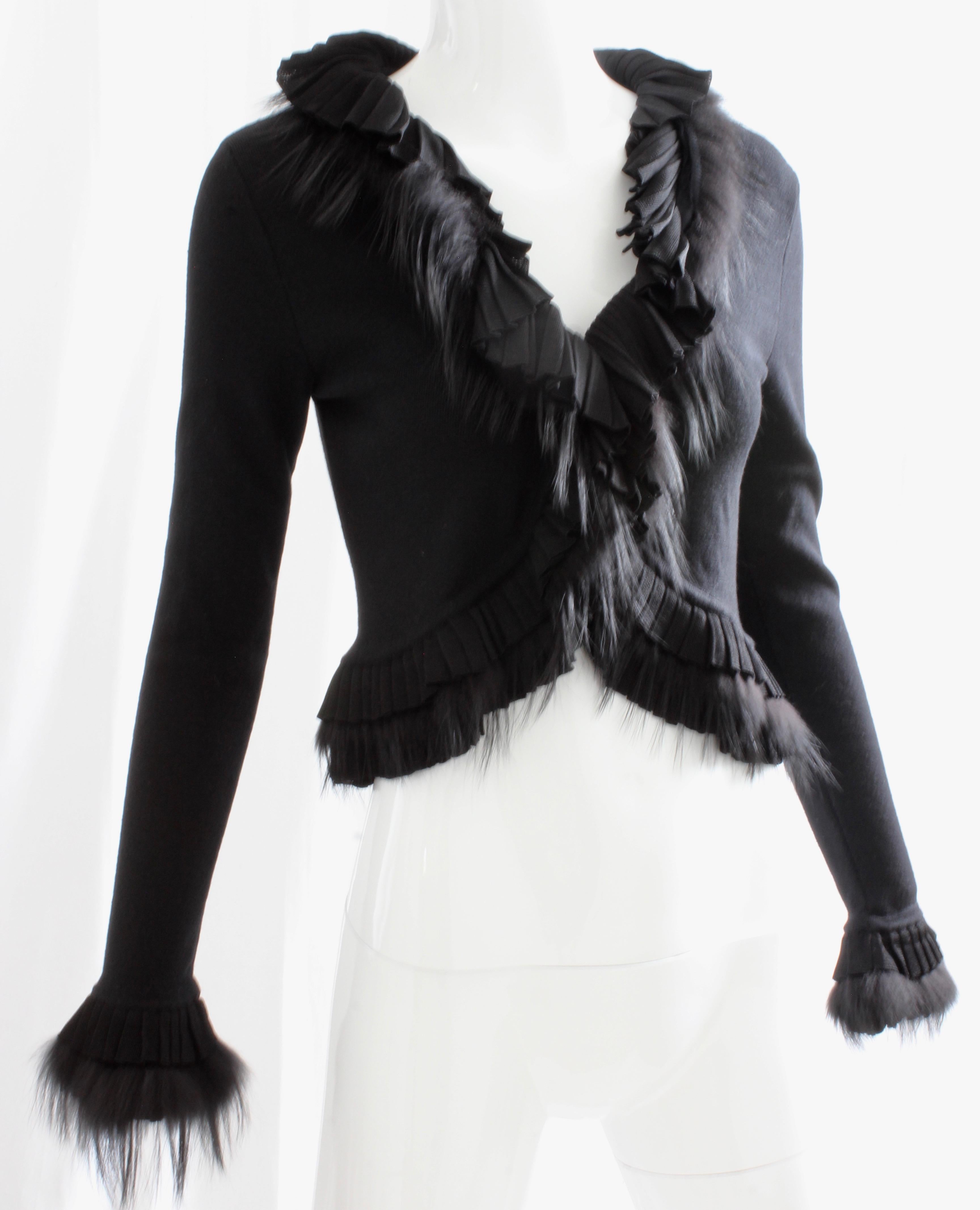 Here's a fabulous black knit shrug with fur trim and knit ruffle detailing from Roberto Cavalli.  Tagged size 40, it measures: shoulders - 16in, bust - 35in, waist - 27in, sleeves - 25in, shoulder to hem - 17.5in. Unlined; fastens with two hook/eye