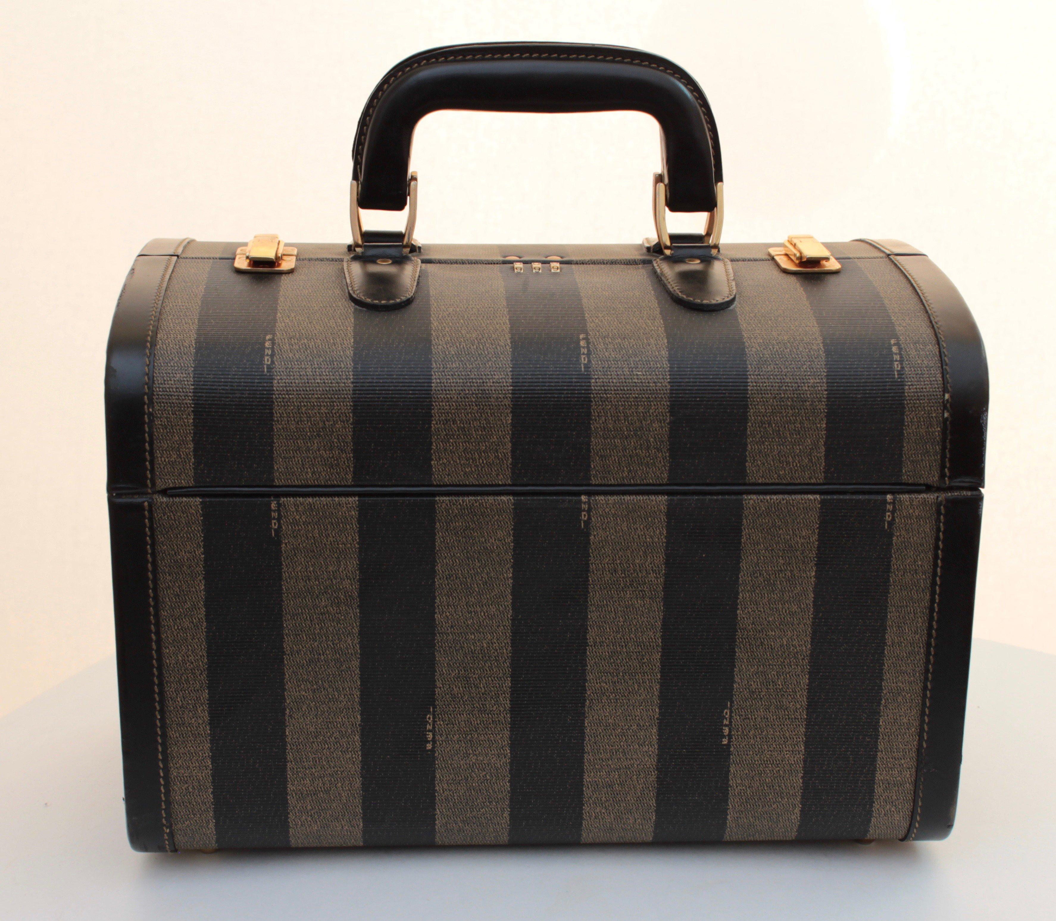Travel in style with this super rare train case or carry on bag by Fendi. Made from their striped Pequin canvas, it's trimmed in leather and features two gold metal clasps and a combination lock (we do not have the combination). Inside, it's lined