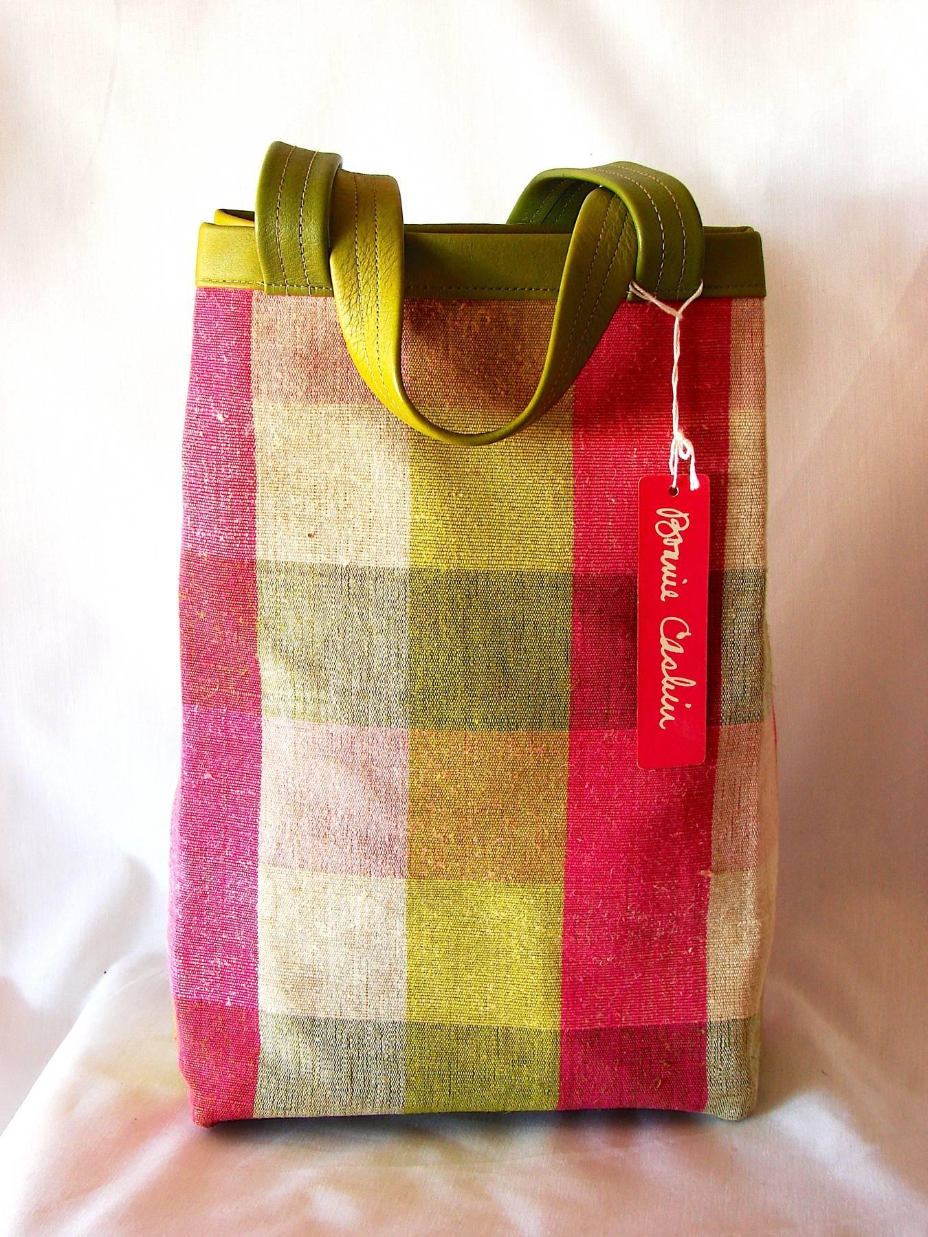 This lovely striped plaid canvas and leather tote bag was designed by Bonnie Cashin during her time at Coach in NYC, circa 1960s.  The canvas features Bonnie's signature vibrant palette in shades of pink, lime and oatmeal, and the bag is trimmed in