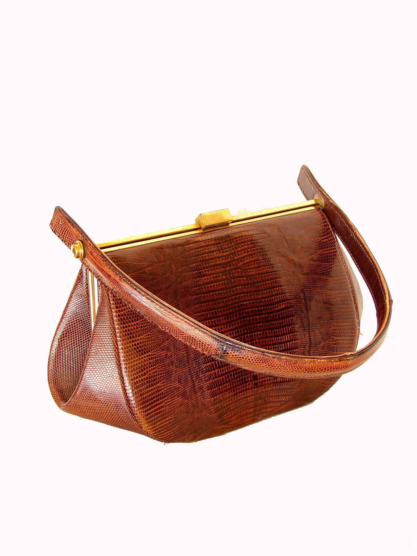 This lovely exotic skin bag was created by Harry Revitz for 'Exact Match by Revits' in the early 1960s.  Made from a honey brown lizard skin, this bag is structured with a gold metal top clasp and hinged top handle. Inside, it's lined in tan leather