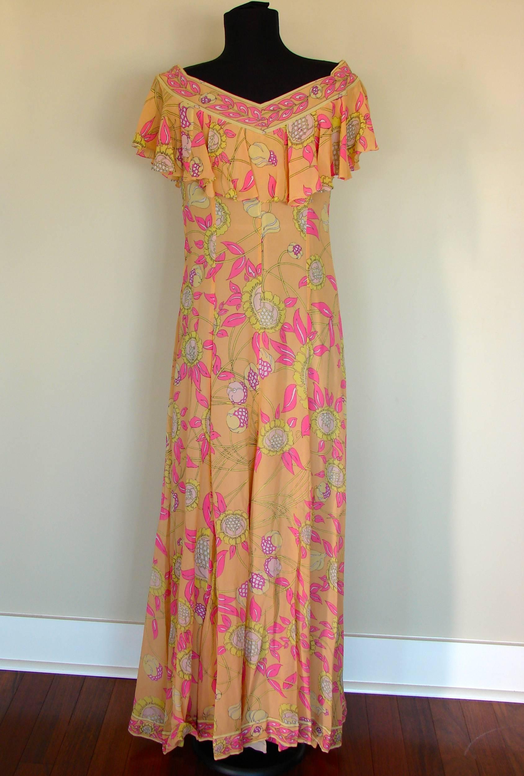 Incredible silk chiffon maxi dress from Emilio Pucci features a bold sunflower print in shades of peach, pink, yellow and white. Ruffled top can be worn off shoulders if so desired. Fastens with side zip and fully lined in nude crepe. This piece is