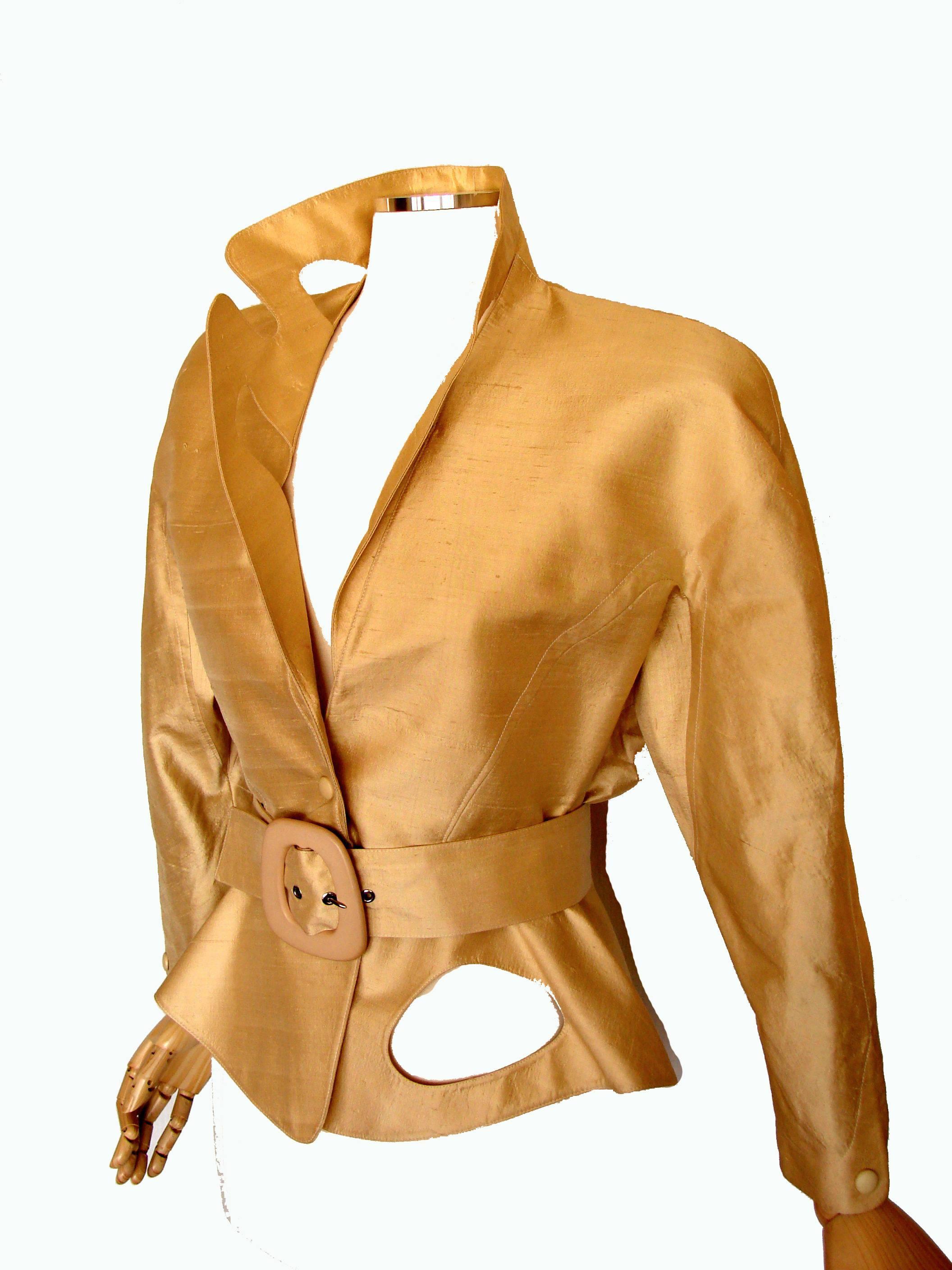 This incredible jacket & belt set was designed by Thierry Mugler Paris in the early 1980s.  Made from a duopioni silk fabric in a champagne gold shade, this jacket features one notched collar and the other shawl shaped, as well as abstract cut