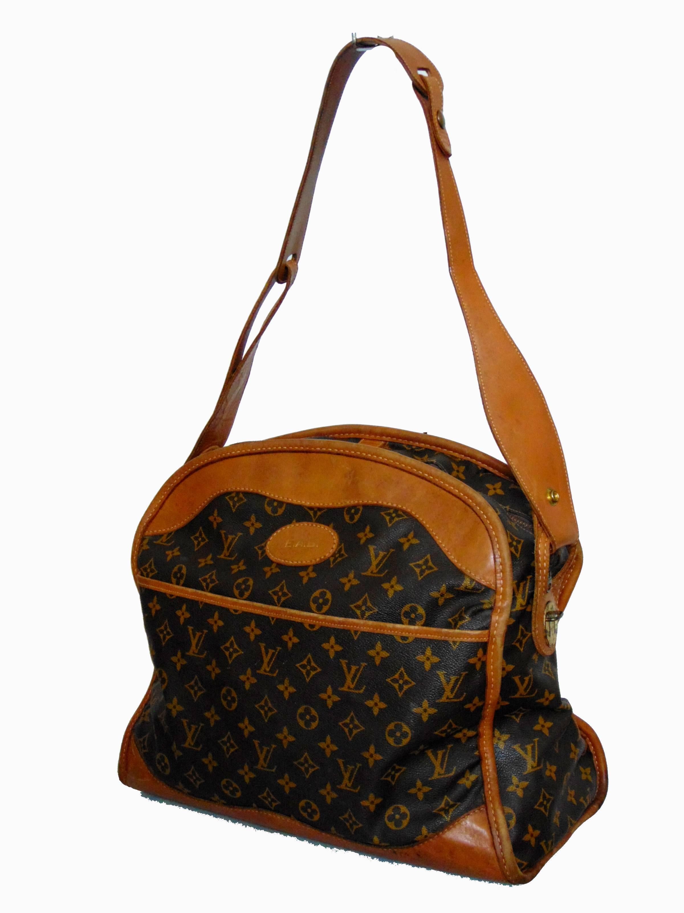 This vintage travel bag was made in the USA by The French Company under special license from Louis Vuitton, likely in the mid 1970s.  Made from Vuitton's signature monogram canvas, this piece is trimmed in tan leather.  It features an open front
