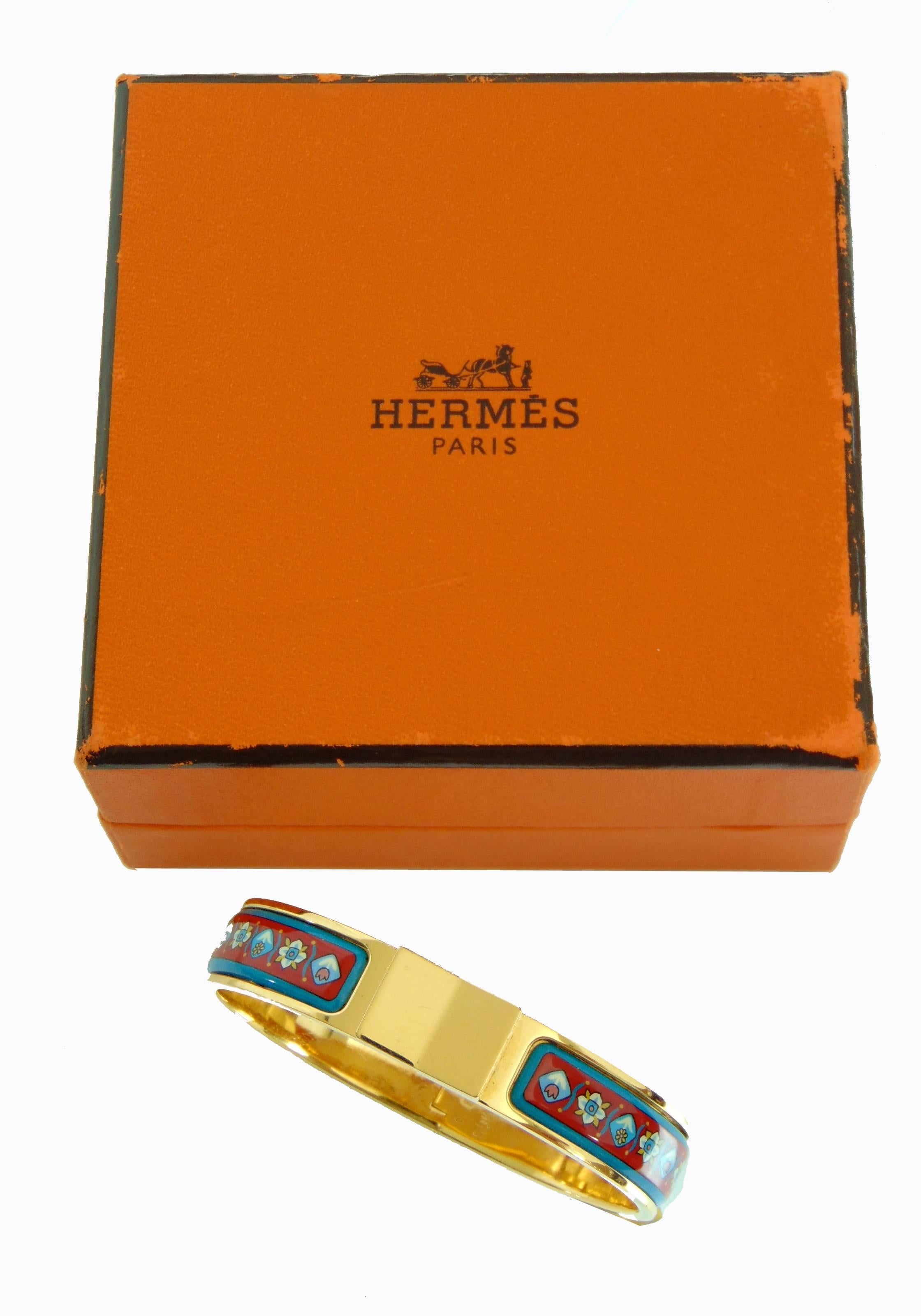 This gold Hermes Clic Clac bracelet is from their 2006 collection and is hard to find in this red and blue floral color way.  In excellent condition for its age, we note scratching to the gold hardware from prior wear.  Comes with box (box shows