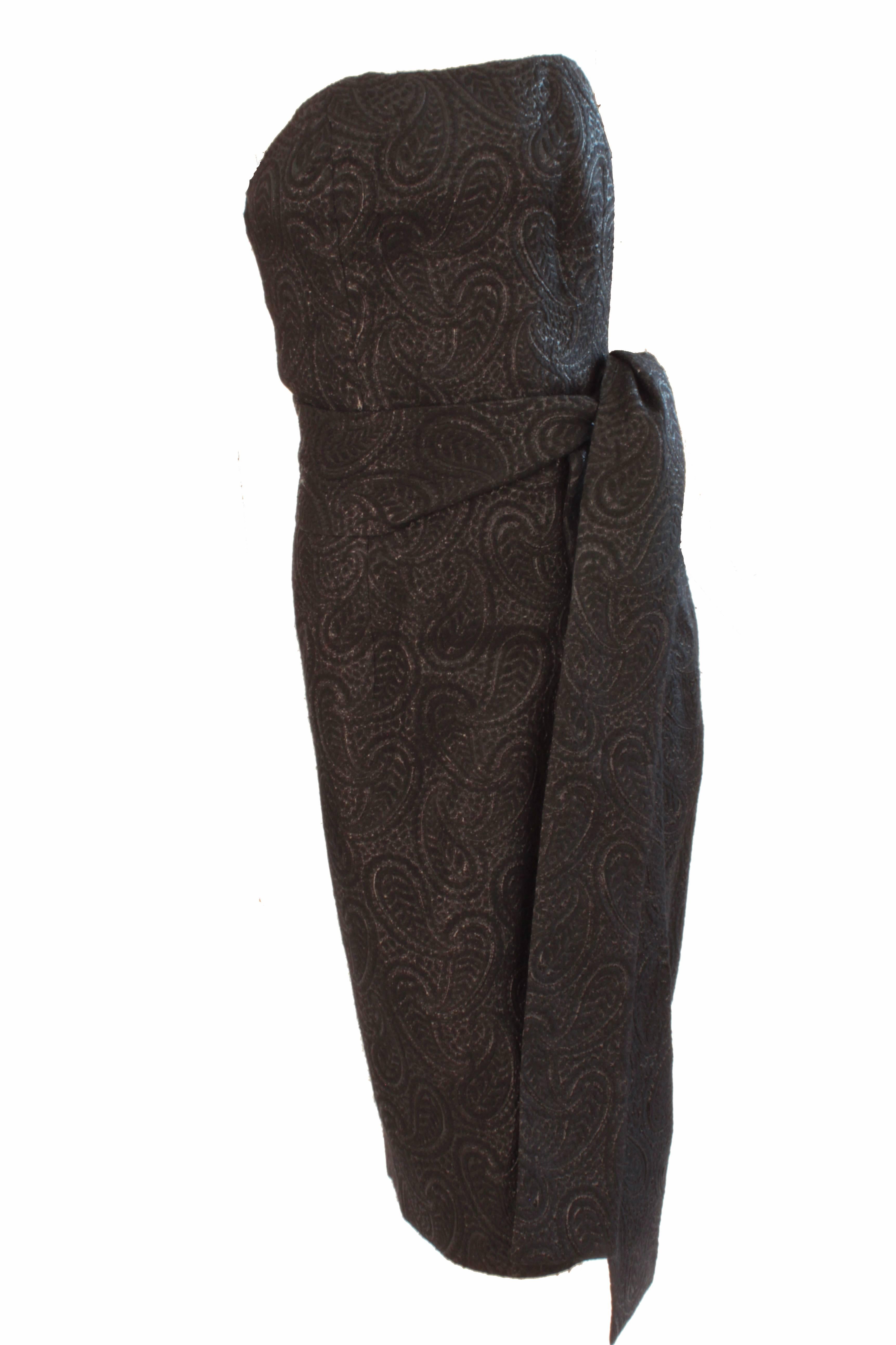 This sparkling little black dress was made by Givenchy, most likely in the late 1960s.  Made from a silk, wool and lurex blend fabric, it features a paisley motif throughout and comes with a matching thick wrap belt or scarf.  Fully-lined, it