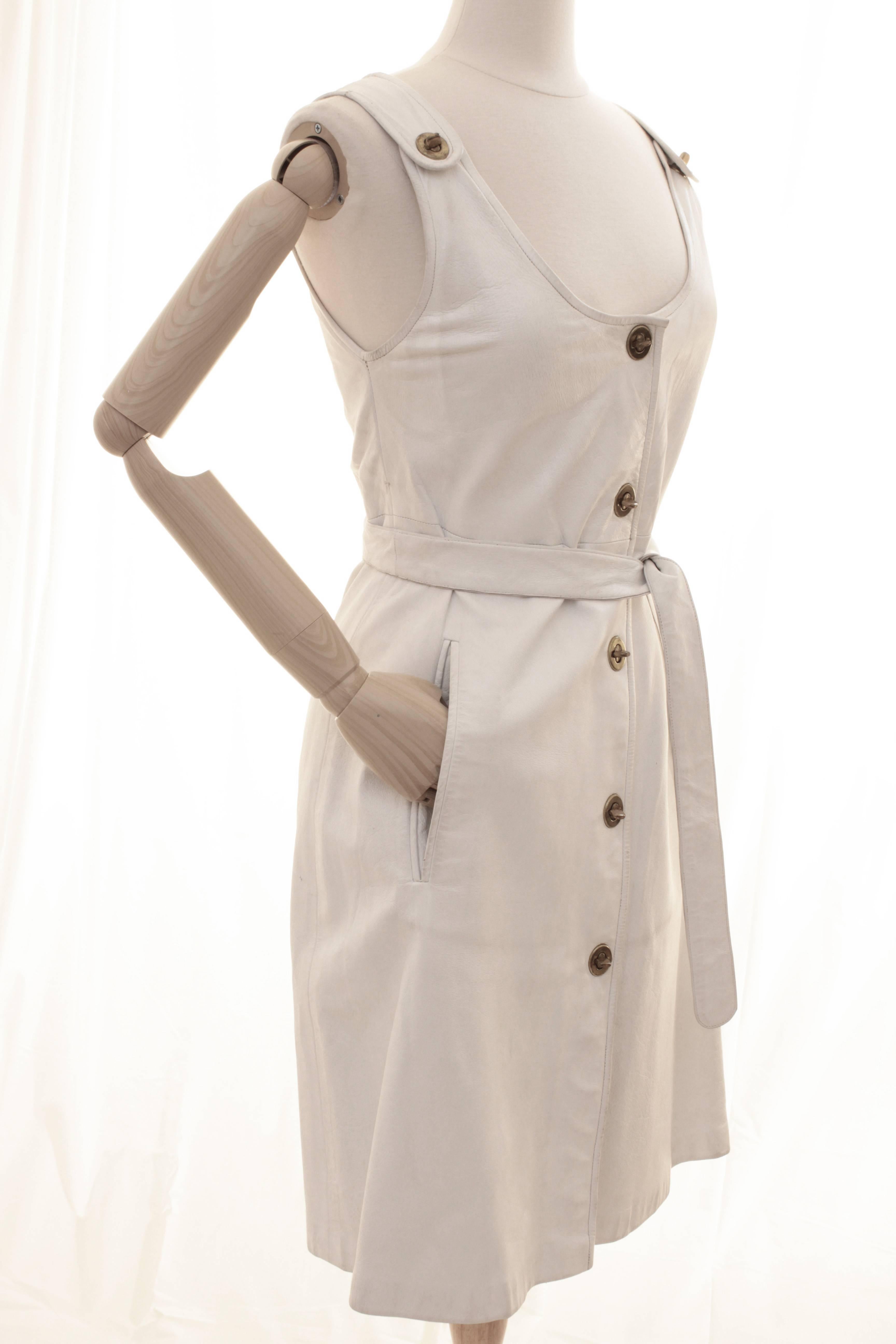 This incredibly rare ensemble was made by Bonnie Cashin during her time at Sills and includes a white leather dress with turn locks, a matching white leather belt and a pair of white leather gloves with brass turn locks.  Fully-lined, the dress has