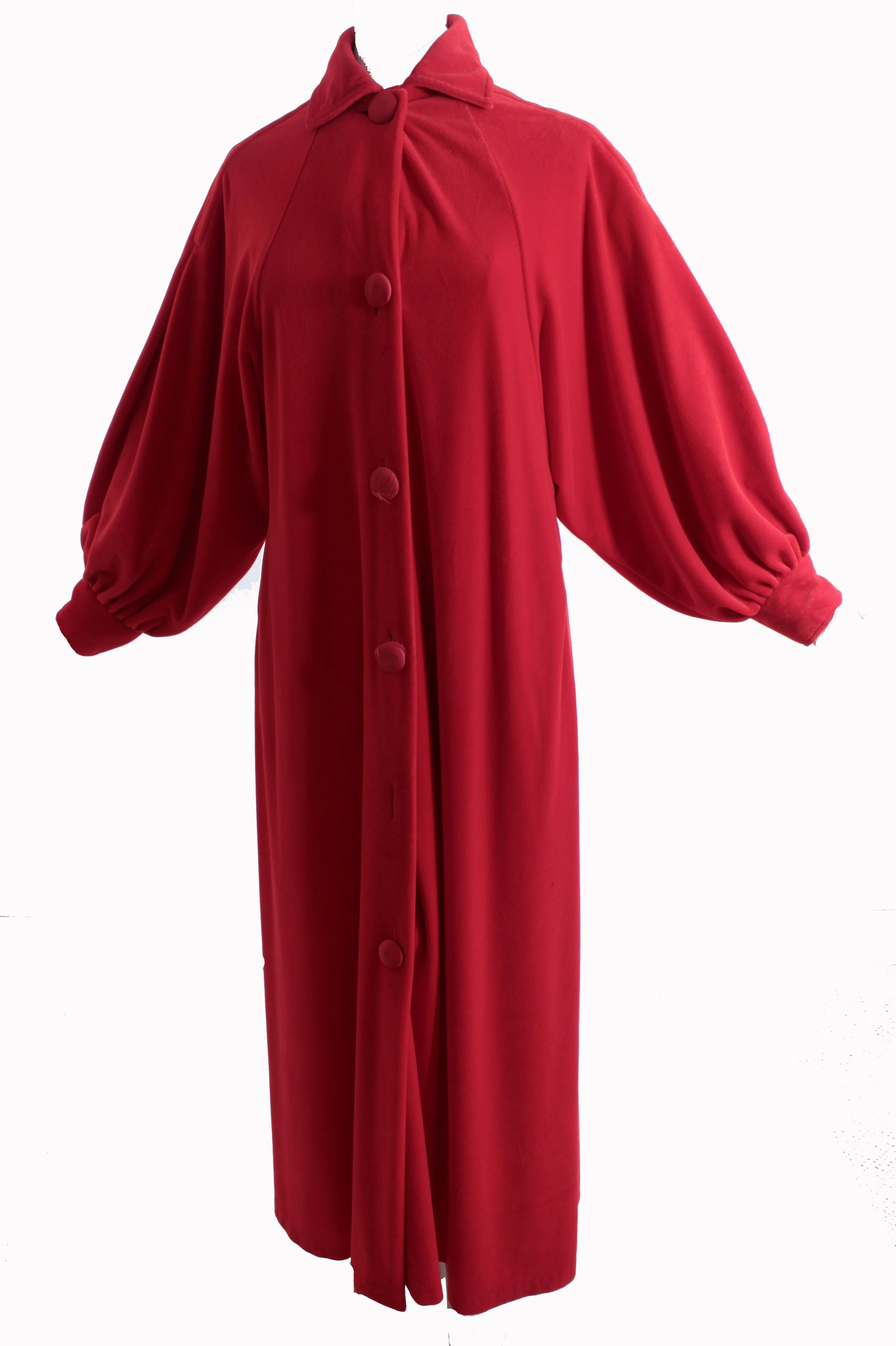 This red velvet robe was made by Pierre Cardin, most likely in the late 50s or early 60s.  It features billowy Dolmen sleeves that fasten at the wrists with a satin covered button, and satin covered buttons down the front.  Unlined with side