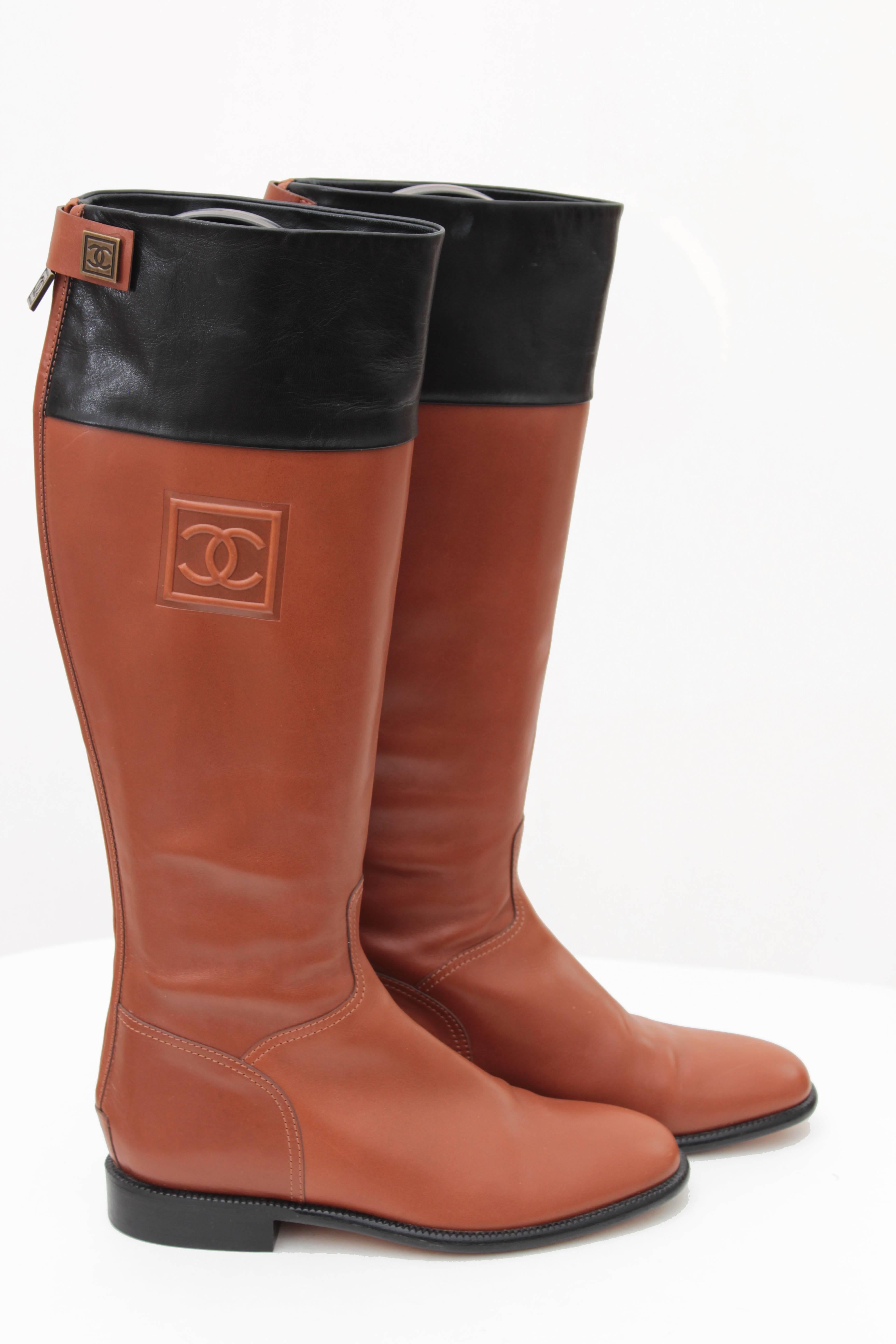 Here's a pair of riding boots from Chanel.  Made from black and tan leather, they fasten in back with zippers and CC logo snaps.  In excellent condition, with minor wear to the soles.  Come in their original box (note that box has dings and damage)