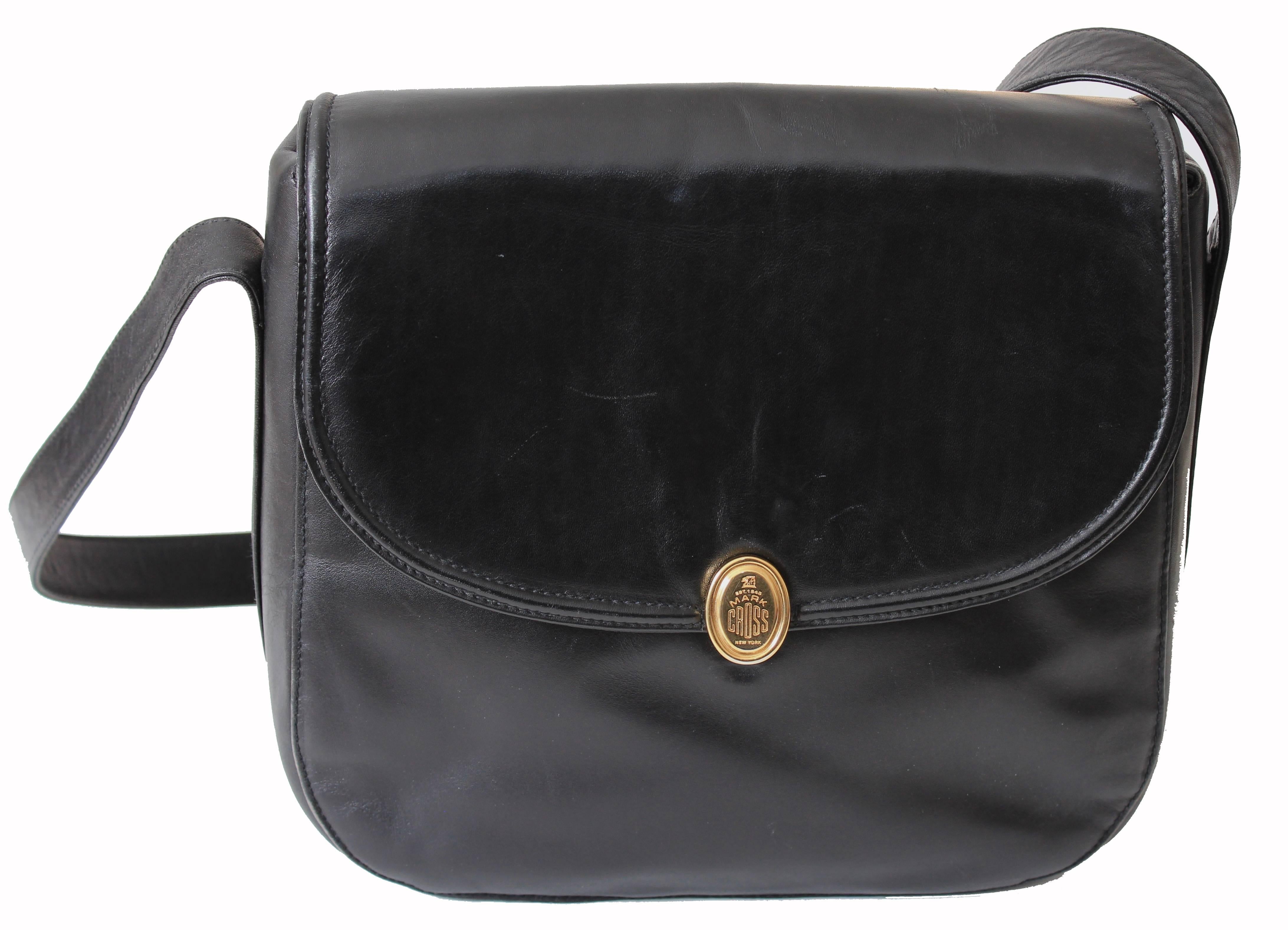 Here's an exquisite black leather messenger bag from Mark Cross, likely made in the late 90s.  Made from supple black calfskin leather, it features a flat exterior pocket and fastens with a gold logo clasp.  The interior is lined in tan pigskin and