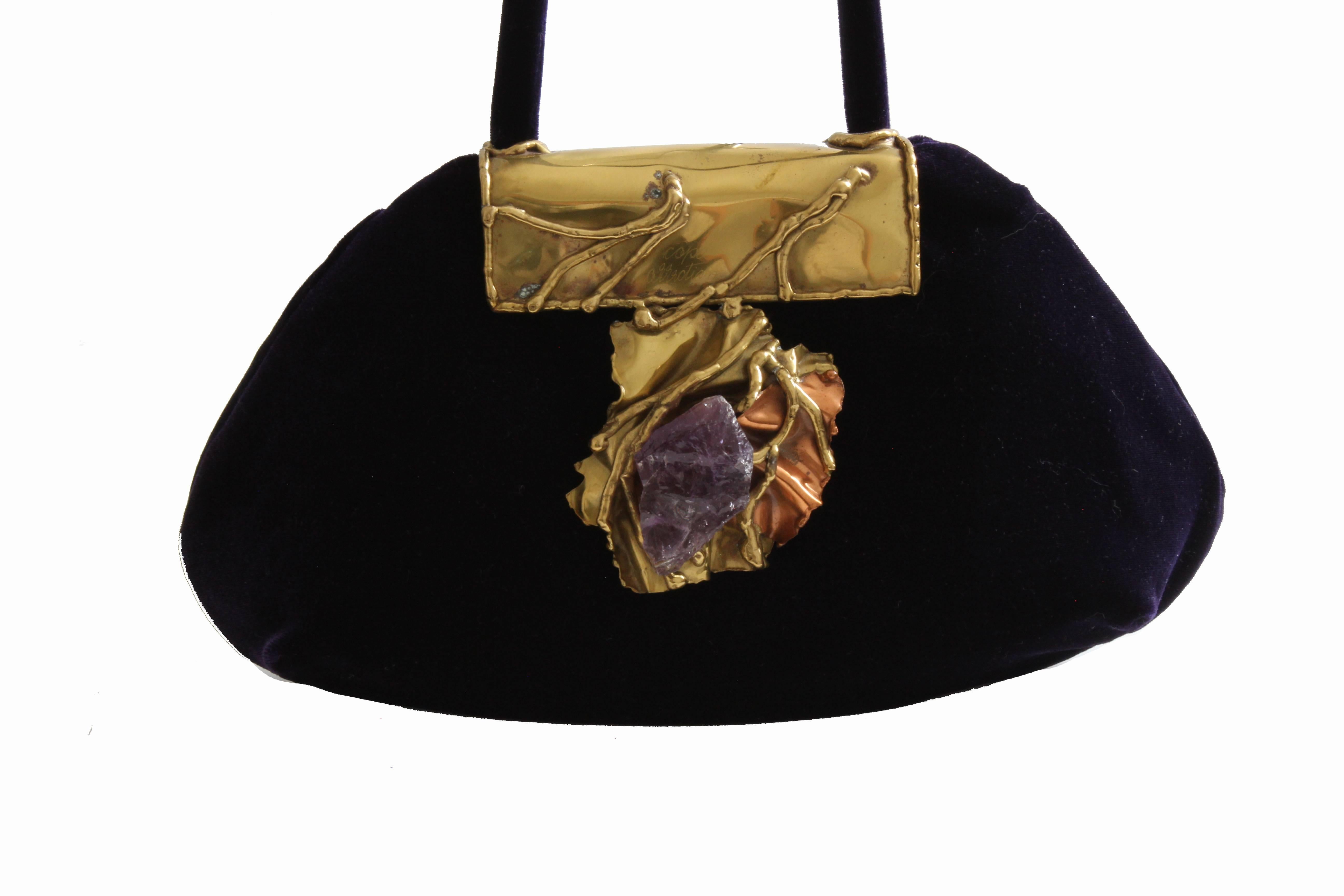 This one of a kind bag was made by artistan Carvalhu Rio Ernandes for his Copa Collection, most likely in the late 70s, early 80s.  Made from royal purple silk velvet, this bag is lined in floral embroidered silk and features a large brass piece