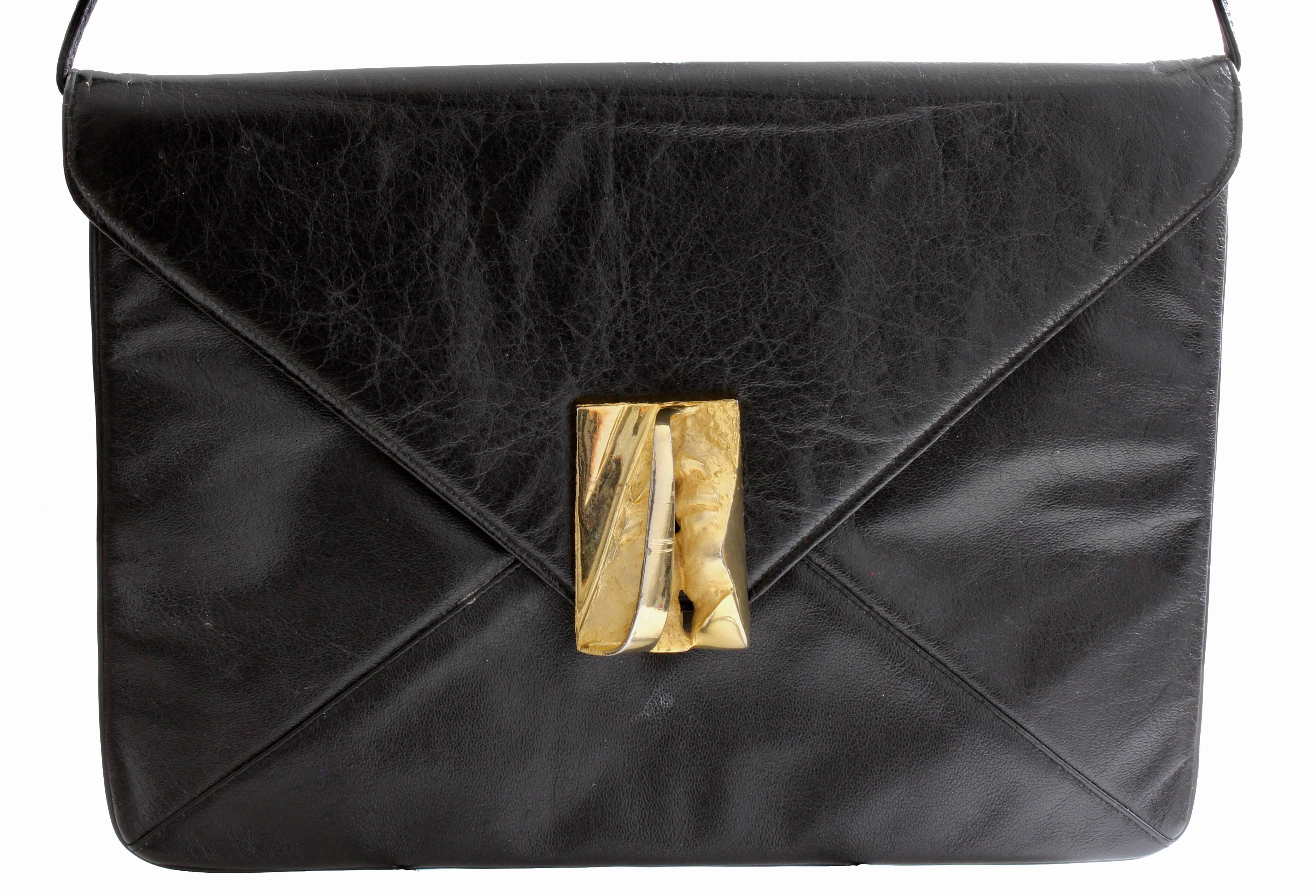 This unusual envelope clutch or shoulder bag was made by Harry Rosenfeld, most likely in the mid 1960s.  Made from black leather, it features a sculpted abstract figural face clasp in gold metal and a removable shoulder strap.  The interior is lined