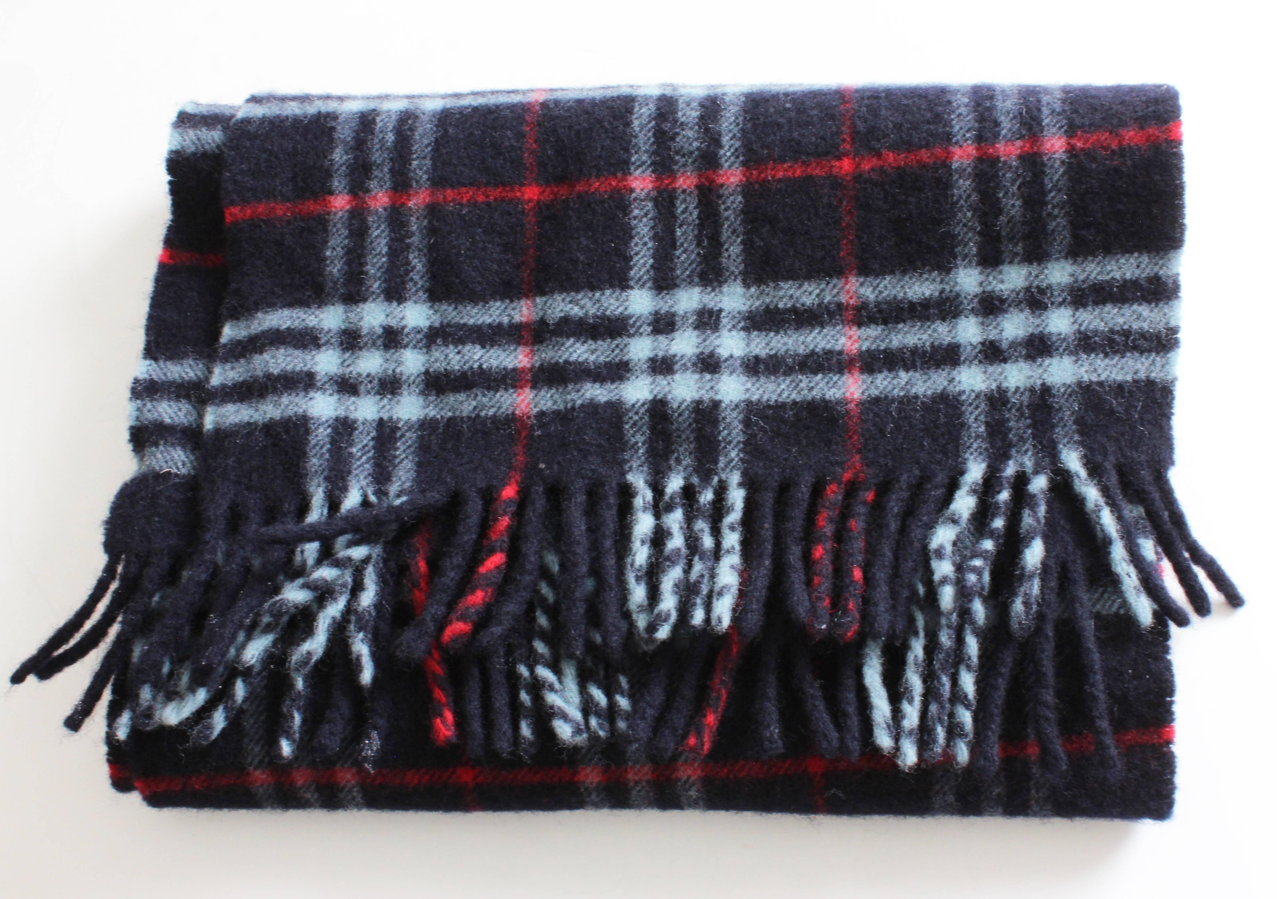 Here's a classic lambswool scarf from Burberry's London in a blue red and white check plaid.  It measures 72in L x 13in W.  In good preowned condition, we note signs of previous wear including some light piling here and there.  Tagged BURBERRYS OF
