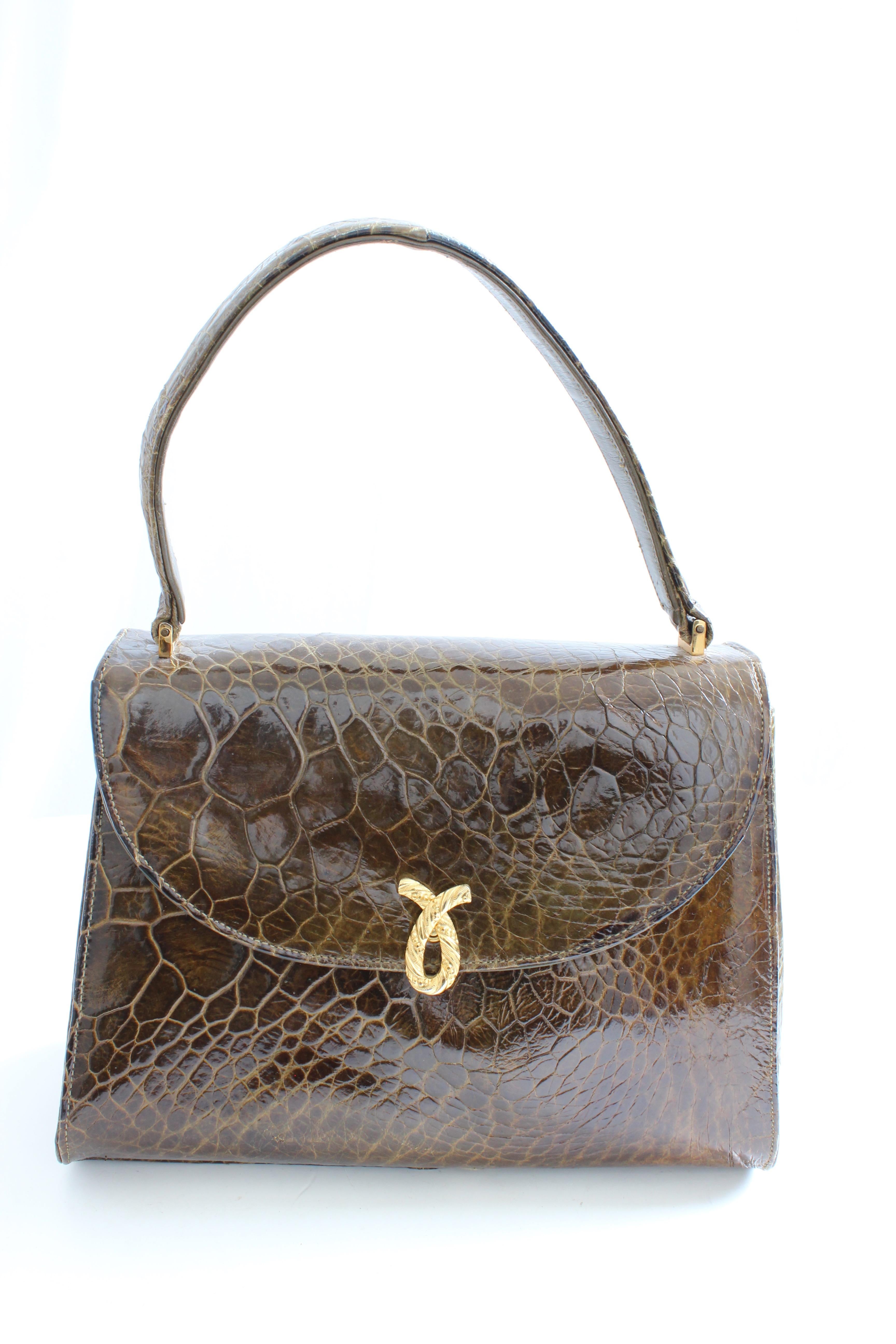 This pretty vintage alligator bag was made by BELLESTONE, most likely in the late 1950s.  Made from a glossy brown alligator hide, it features a gold decorative clasp and is lined in beige leather.  Comes with its original coin purse and mirror,