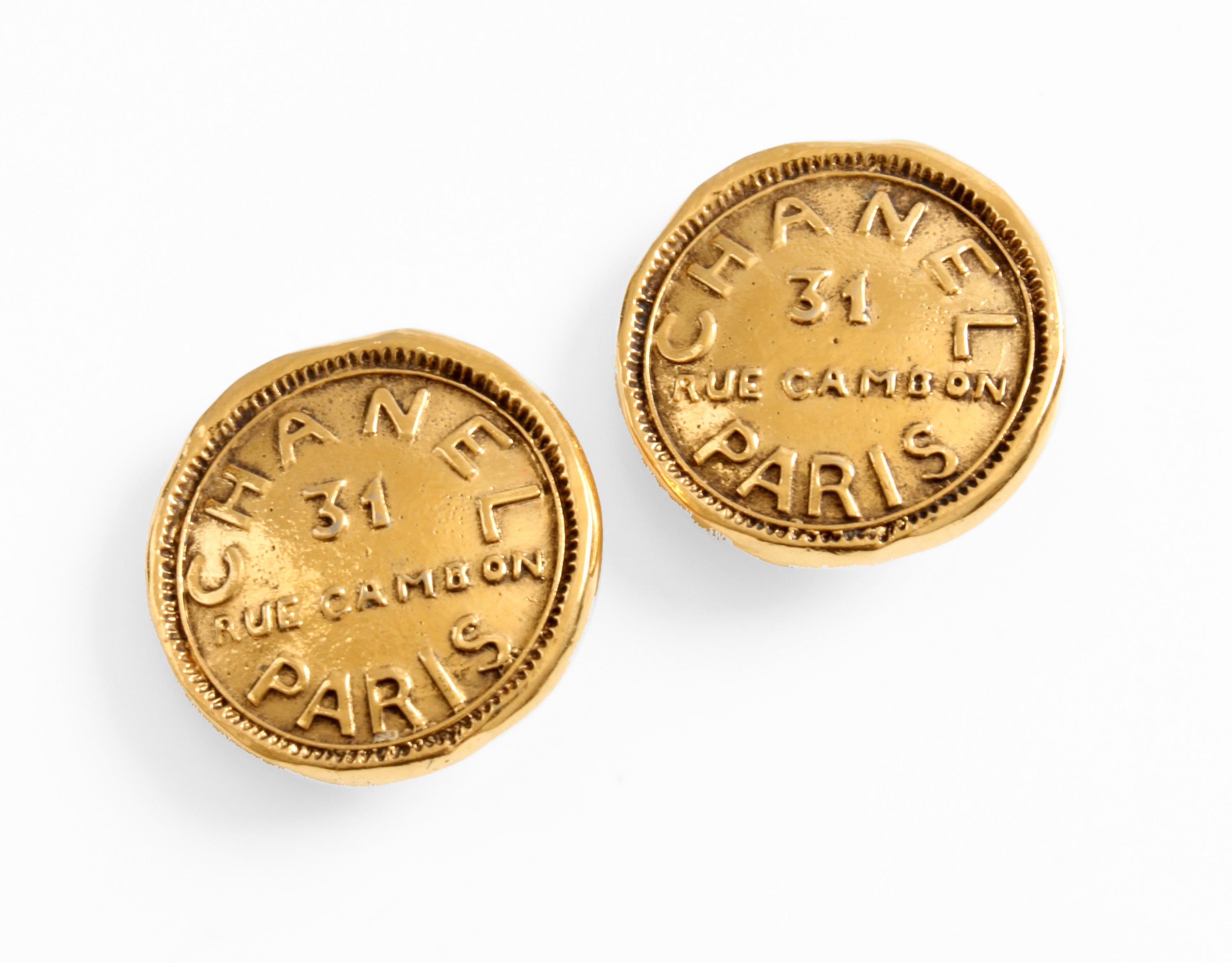 These chic clip-style earrings were made by Chanel, most likely in the early 1980s.  Made from gold metal, they features round button-style fronts with CHANEL 31 RUE CAMBON PARIS in bold graphic letters.  In good preowned condition given their age,